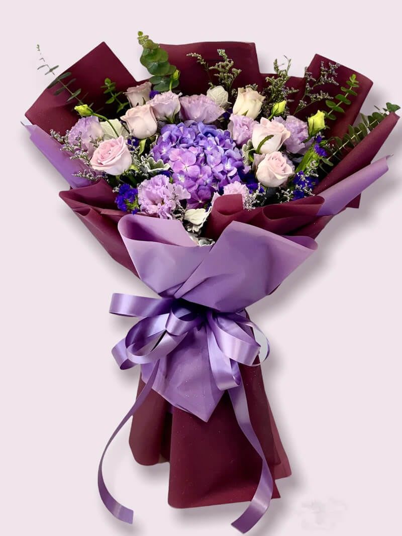 Bouquet of purple and pink flowers wrapped in burgundy and lavender paper