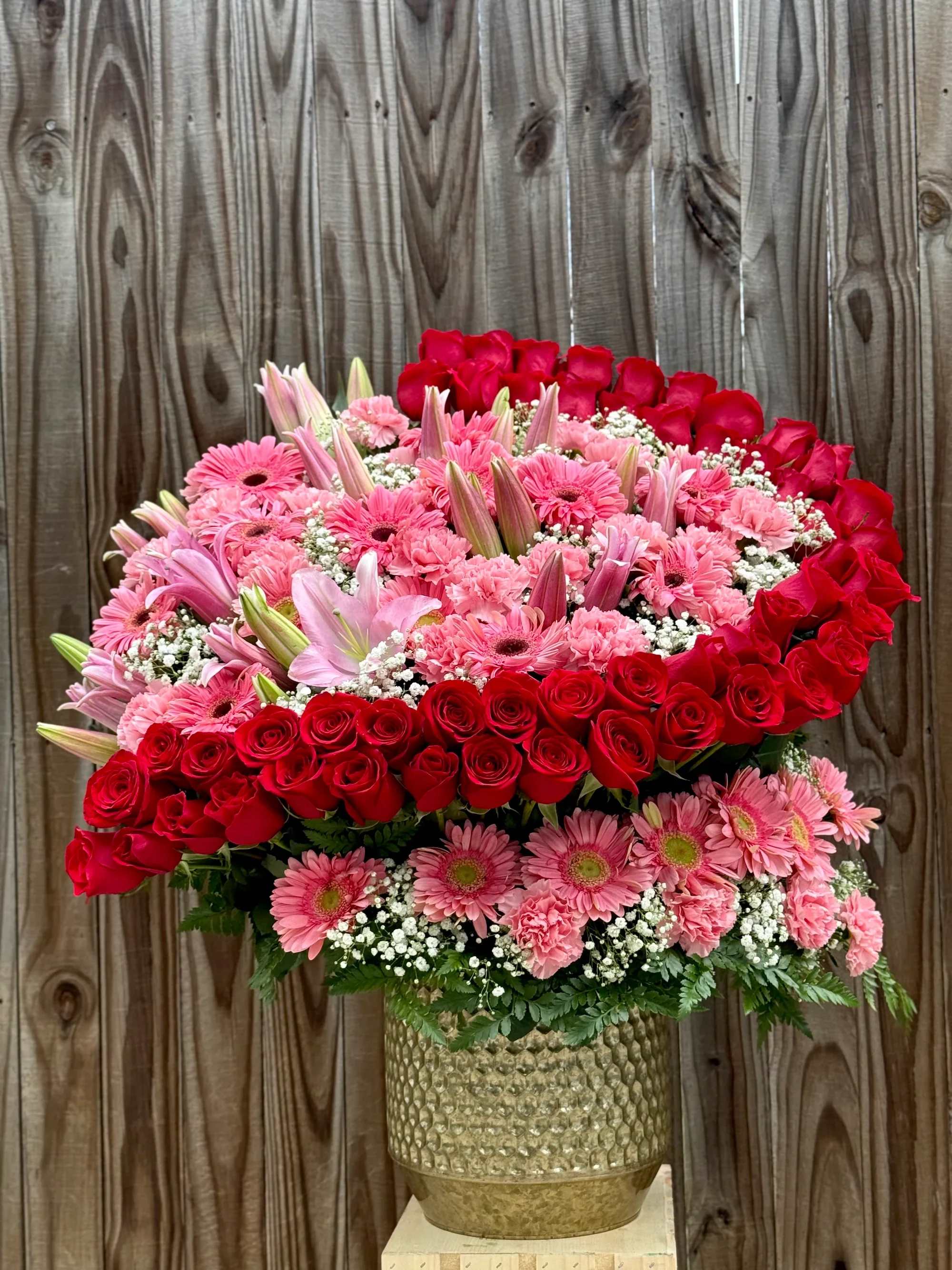 Arreglo de media luna 2 - Hermoso arreglo floral diseñado para sorprender y expresar amor, ternura y elegancia. Este arreglo combina delicadas rosas rojas, gerberas rosadas, lirios rosados, claveles y detalles de baby’s breath, creando una presentación romántica y llena de vida.  Las rosas rojas simbolizan el amor profundo, mientras que las flores rosadas aportan dulzura y armonía. Todo el arreglo está cuidadosamente colocado en un elegante florero dorado que resalta aún más la belleza de las flores.  Perfecto para ocasiones especiales como:  • Aniversarios • Cumpleaños • Sorpresas románticas • Día de San Valentín • Detalles especiales para alguien querido  Este arreglo floral es ideal para transmitir emociones y hacer que cualquier momento sea inolvidable.   Incluye: Rosas rojas, gerberas rosadas, lirios, claveles, baby’s breath y follaje decorativo.  Entrega disponible para que tu regalo llegue fresco y perfecto.