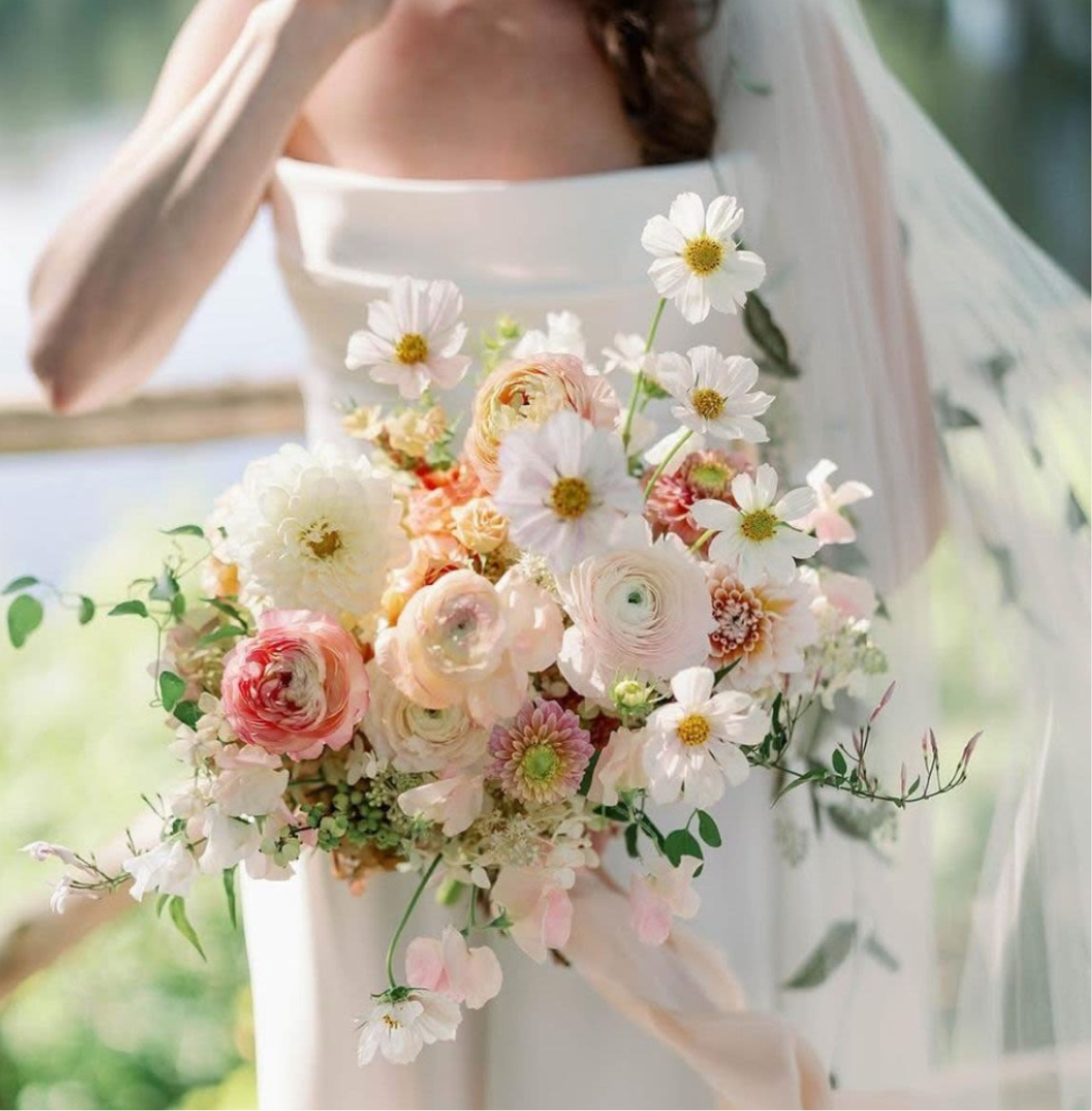 Bride holding a pastel bouquet with white daisies and blush ranunculus