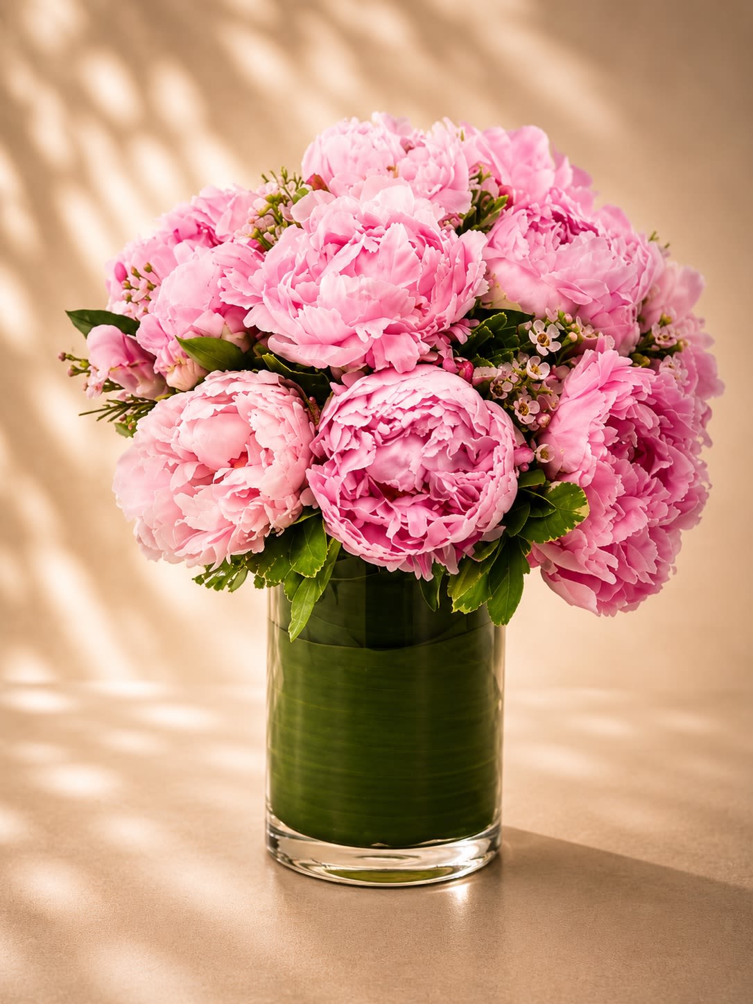 Rosé Peony Couture - An opulent all-peony arrangement featuring lush blush pink peonies artfully gathered in a modern leaf-lined glass vase. Rosé Peony Couture is the definition of timeless luxury — overflowing with soft romantic texture, elegant fullness, and delicate garden beauty.  Peonies symbolize romance, prosperity, happiness, and honor, making this arrangement one of the most beloved luxury floral gifts for meaningful moments and unforgettable celebrations. Designed with premium blooms and accented with subtle garden greenery, this arrangement creates a sophisticated statement that feels both graceful and indulgent.  Perfect for anniversaries, birthdays, Mother’s Day, luxury gifting, baby showers, bridal celebrations, or simply elevating a space with breathtaking floral elegance.  Due to seasonal availability, peonies may arrive in various blooming stages to ensure longer-lasting beauty. During limited peony seasons, select premium garden roses may occasionally be incorporated while maintaining the arrangement’s signature romantic blush aesthetic and luxurious presentation.