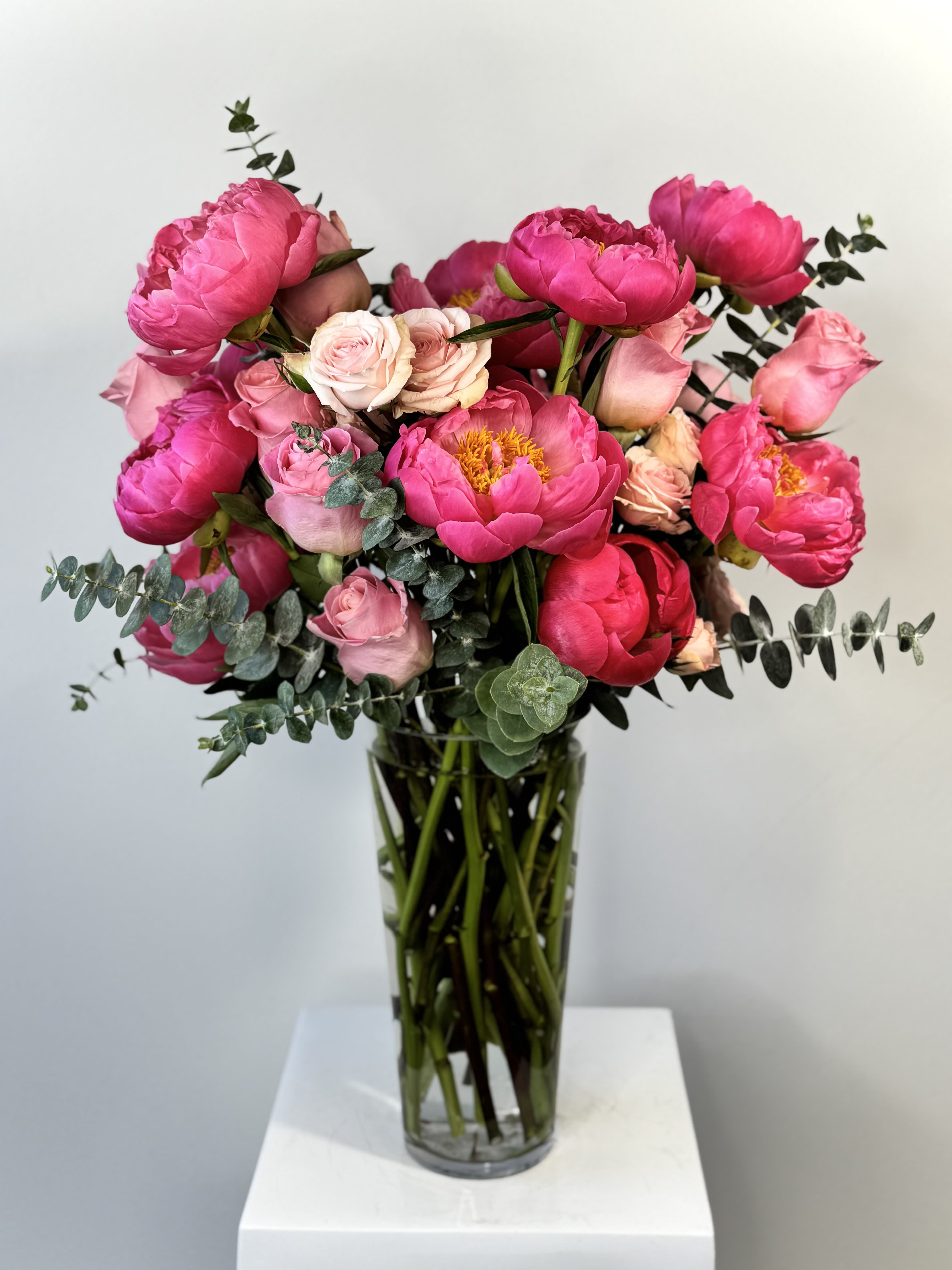 Pink peonies and roses arranged in a clear glass vase