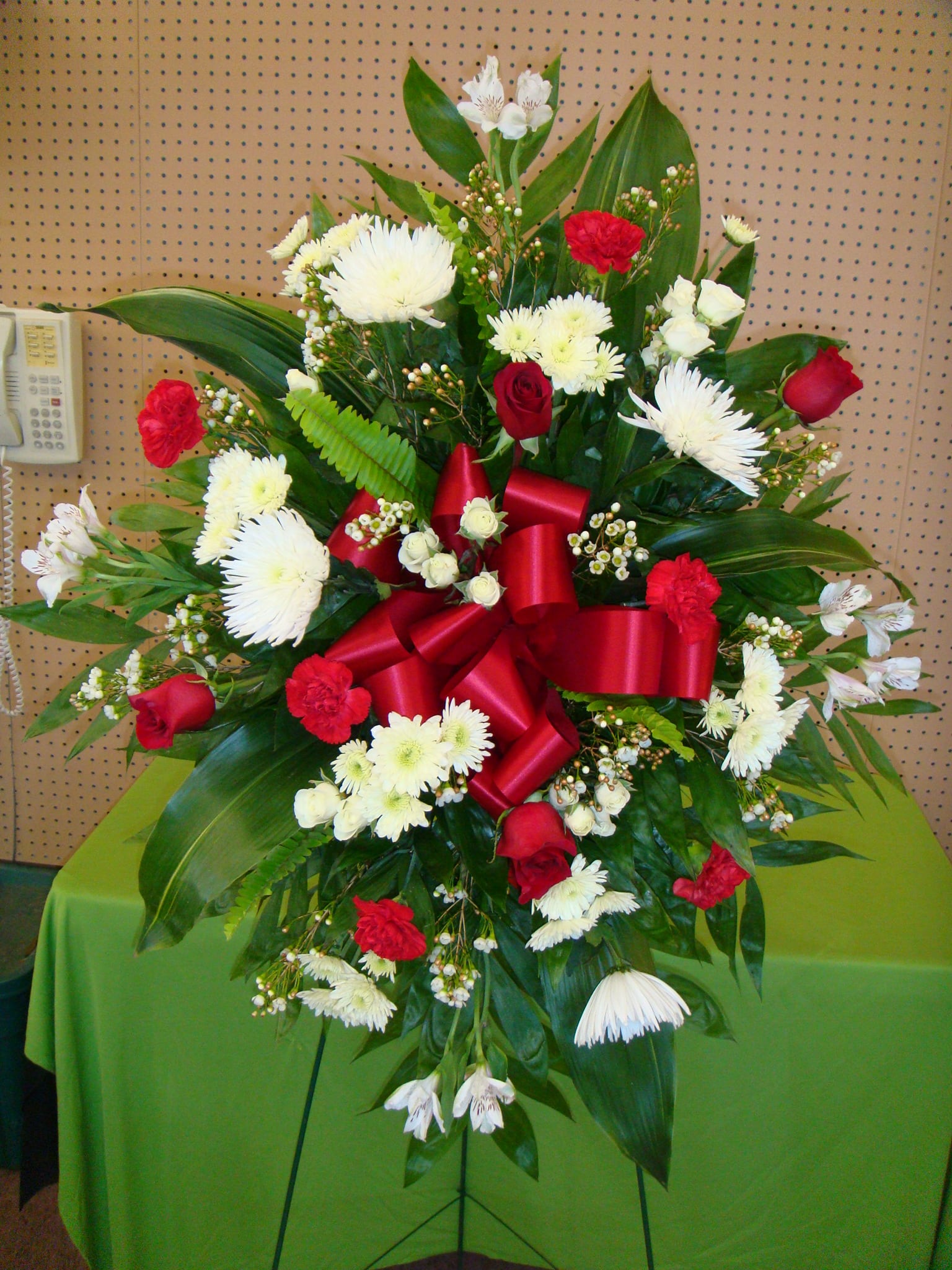 Standing floral spray with red and white flowers and a large red ribbon