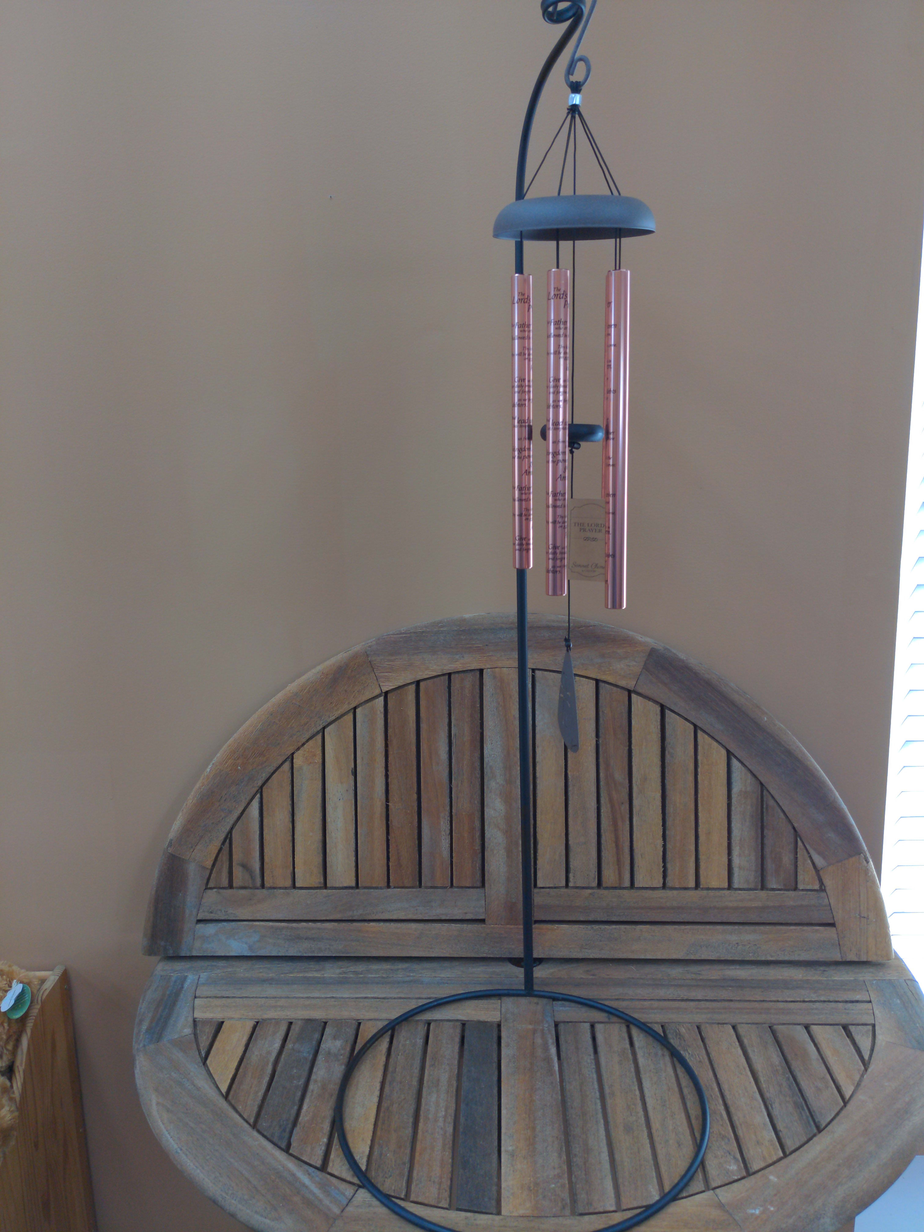 Blue metal wind chime hanging above a wooden bench