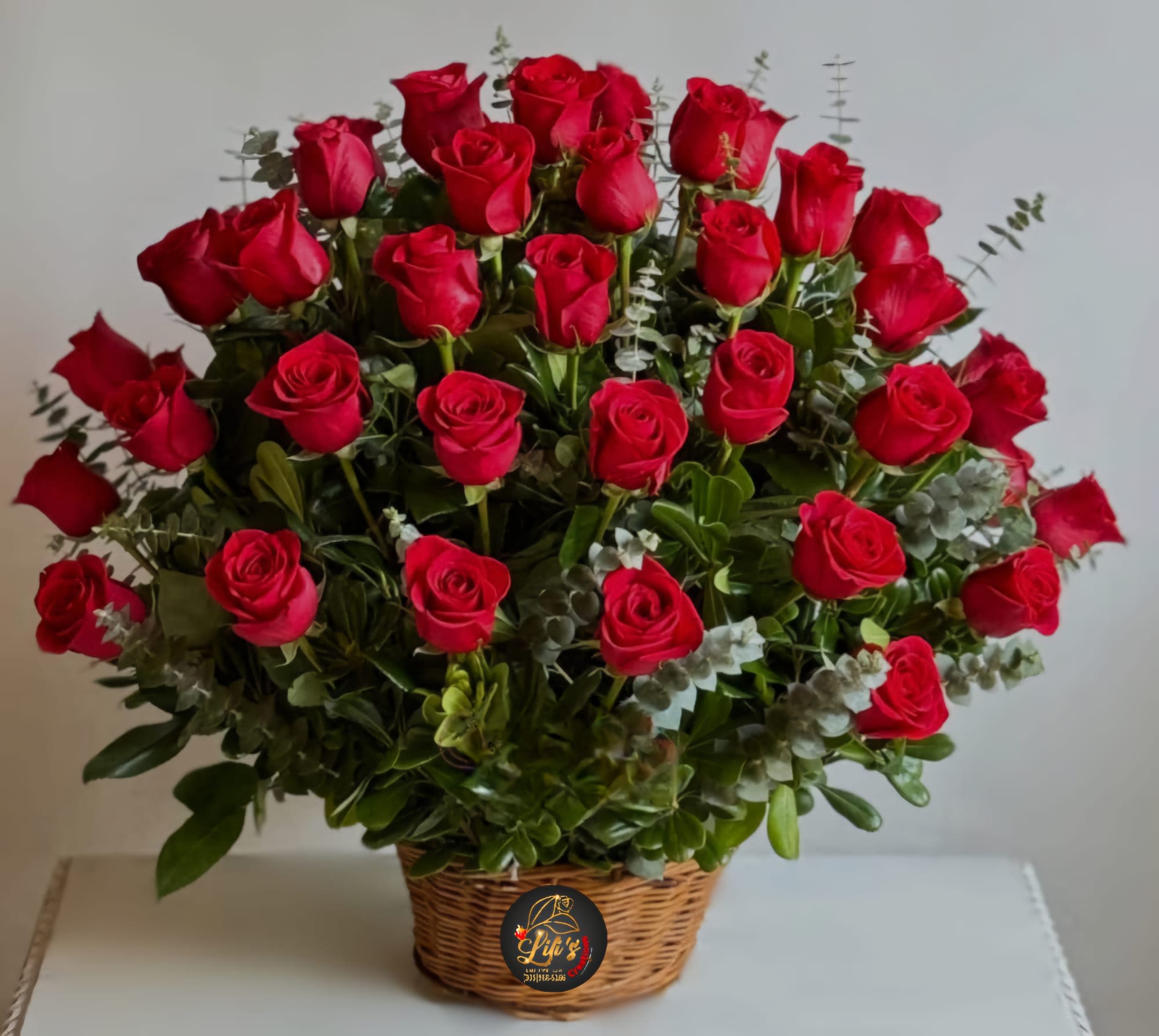 Basket arrangement of red roses with eucalyptus foliage