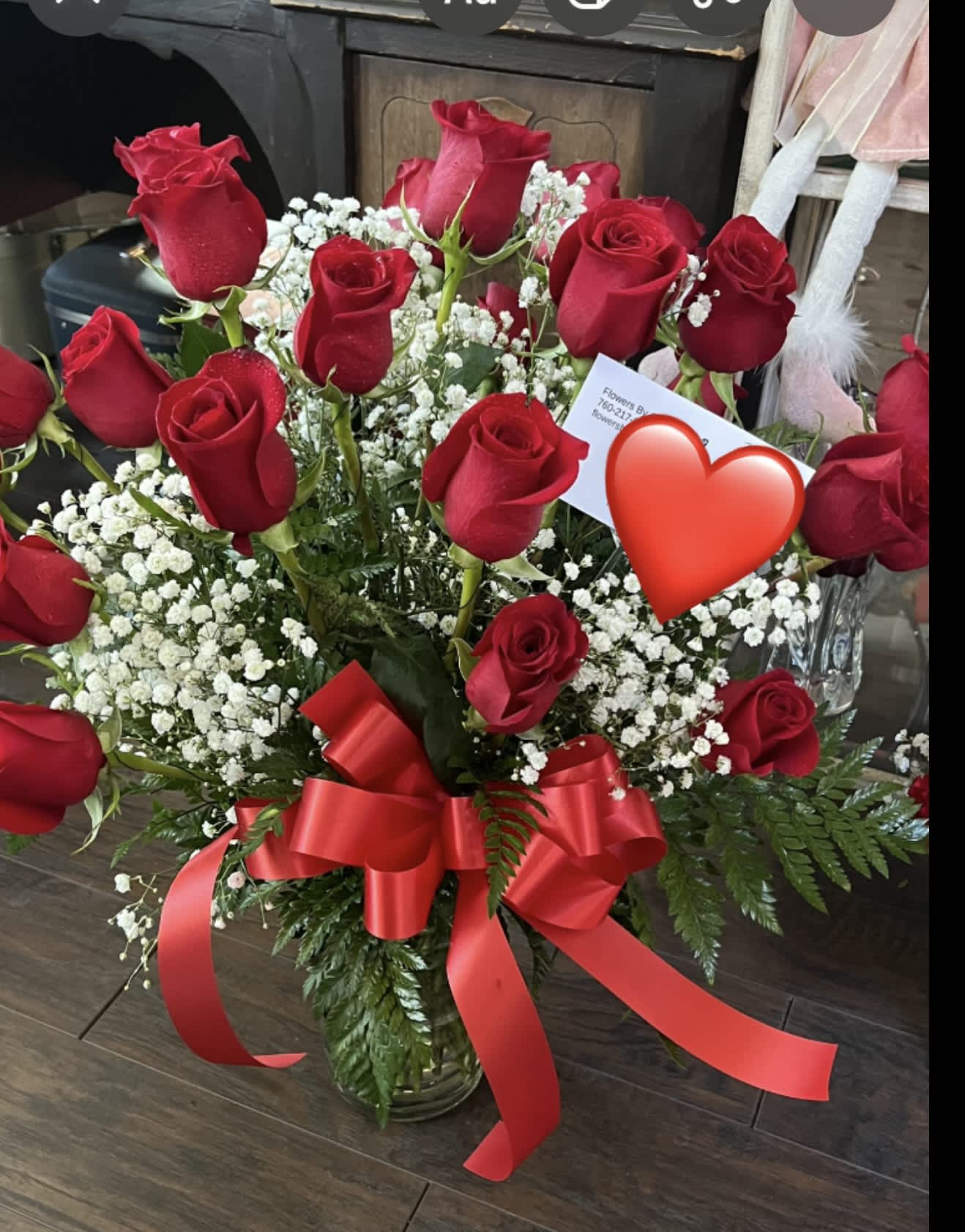 Red roses with baby's breath in a glass vase and red ribbon