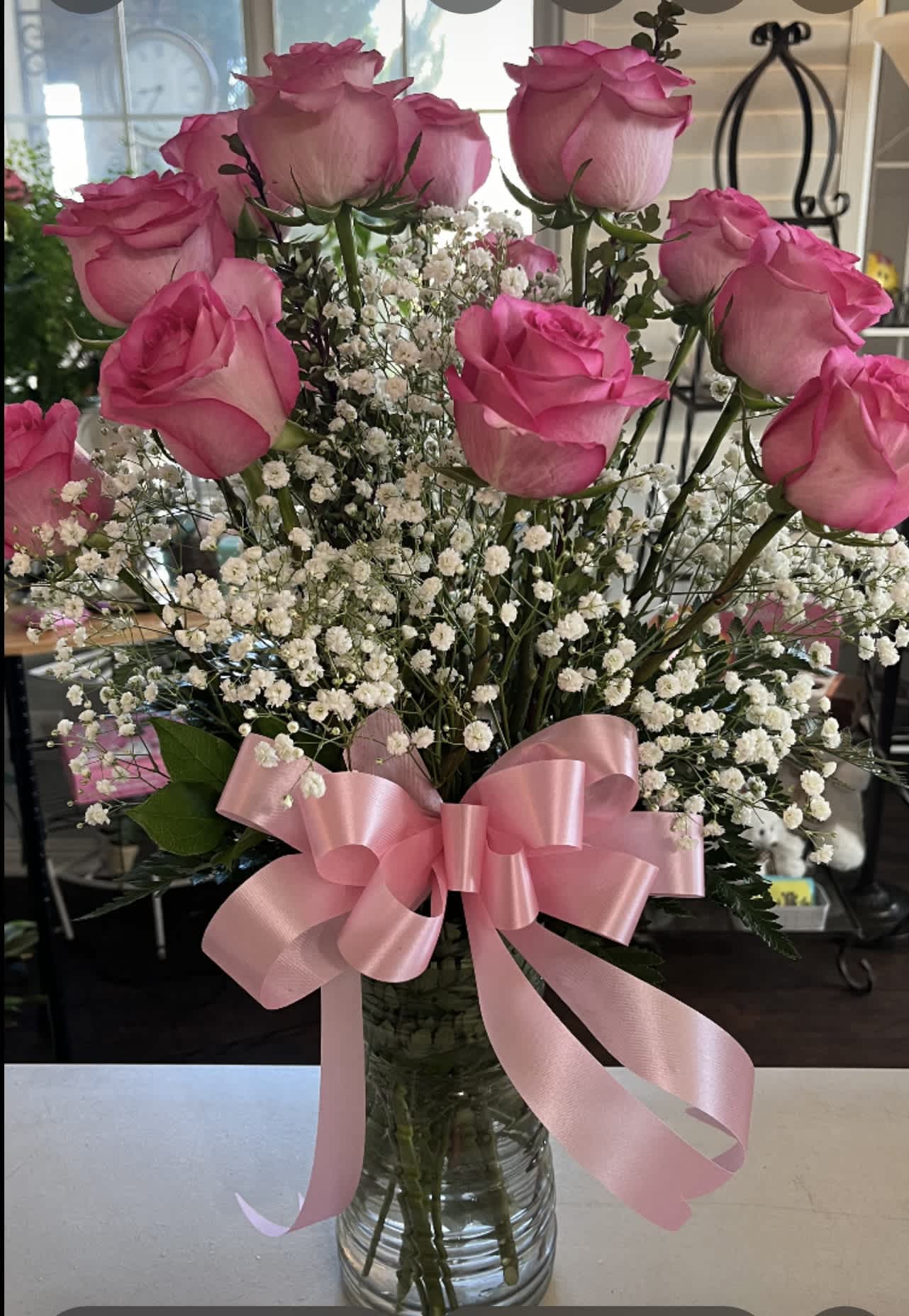 Pink roses with baby's breath in a glass vase and pink ribbon
