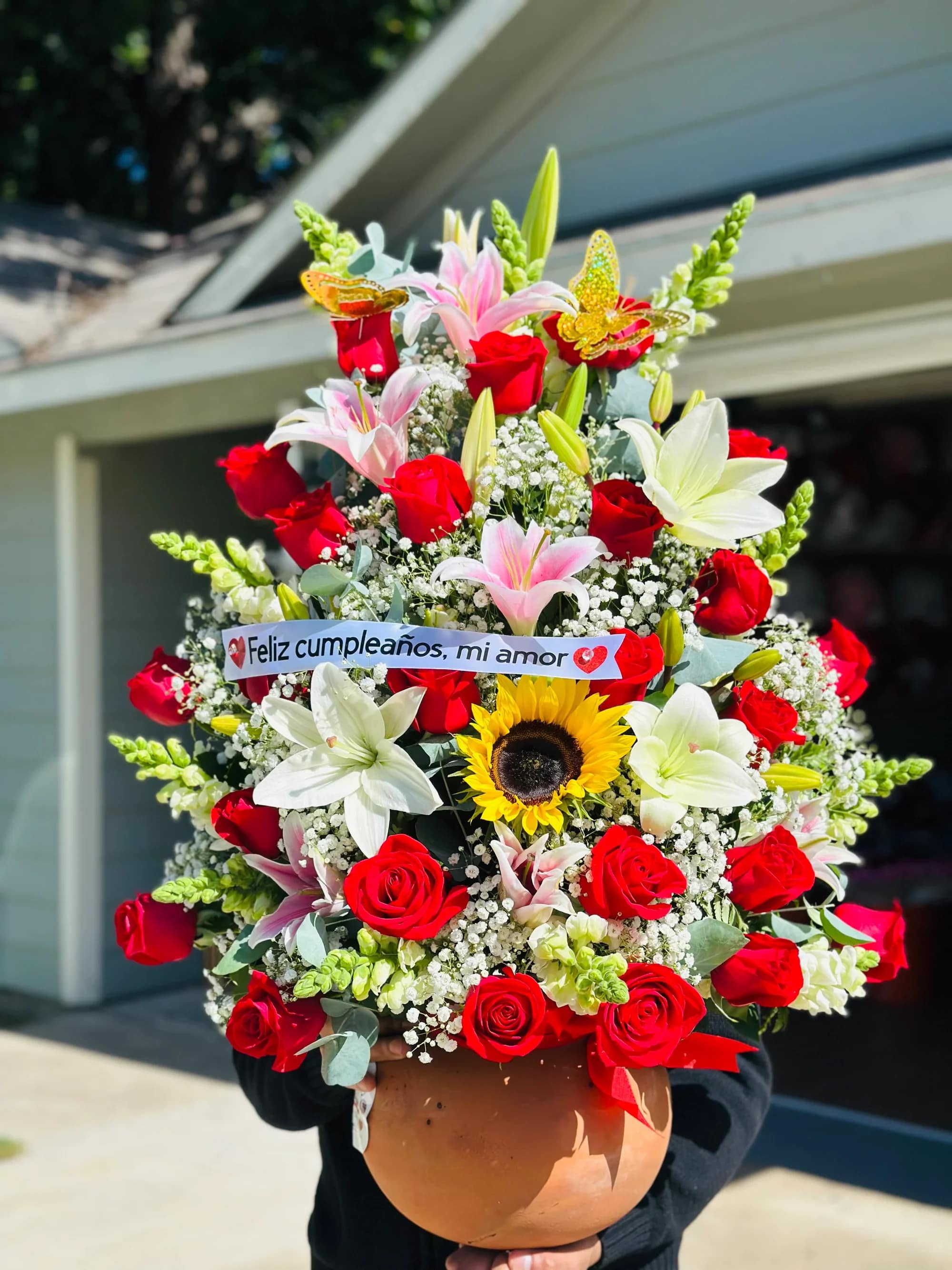 Arreglo en Ollita 3 -  Arreglo Floral Premium con Lirios y Rosas en Base Decorativa   Sorprende con este espectacular arreglo floral de diseño vertical, elaborado con una combinación armoniosa de lirios rosados, rosas en tono pastel, gerberas y flores blancas de complemento.  Su presentación en base decorativa color terracota con detalles delicados y moño rosa lo convierte en un regalo sofisticado y lleno de ternura.  Perfecto para transmitir amor, admiración y dulzura en cualquier ocasión especial.   Detalles del producto:  Lirios rosados protagonistas Rosas color rosa pastel Gerberas rosadas Flores blancas de relleno (baby breath y crisantemos) Base decorativa reutilizable Moño en tono rosa Diseño alto y elegante   Ideal para cumpleaños, aniversario, Día de las Madres, felicitaciones o agradecimientos especiale  Un arreglo floral que destaca por su volumen, frescura y elegancia.