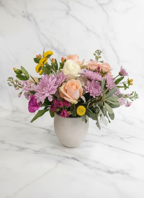 Sweet Serenity  - A lush garden-style arrangement featuring premium roses, spray roses, lavender chrysanthemums, seasonal blooms, and textured greenery designed in a keepsake ceramic vase. Soft shades of blush, lavender, cream, and berry create a charming, feminine design perfect for birthdays, thinking of you, get well wishes, or simply brightening someone's day.