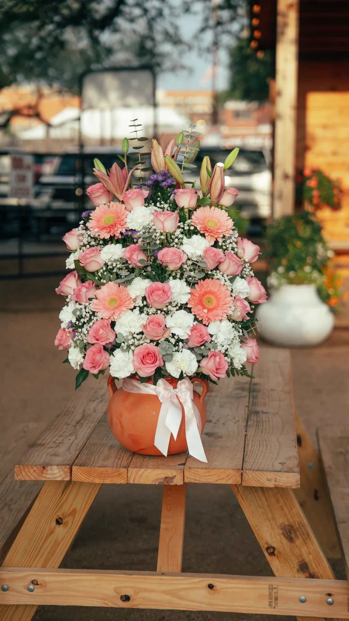 Arreglo en Ollita 9 - Elegante arreglo floral en base artesanal con rosas rosadas, lirios, gerberas y flores frescas en tonos suaves. Un diseño lleno de belleza y delicadeza, ideal para sorprender en cumpleaños, aniversarios o cualquier ocasión especial. Disponible para entrega a domicilio. ¡Ordena en línea hoy!