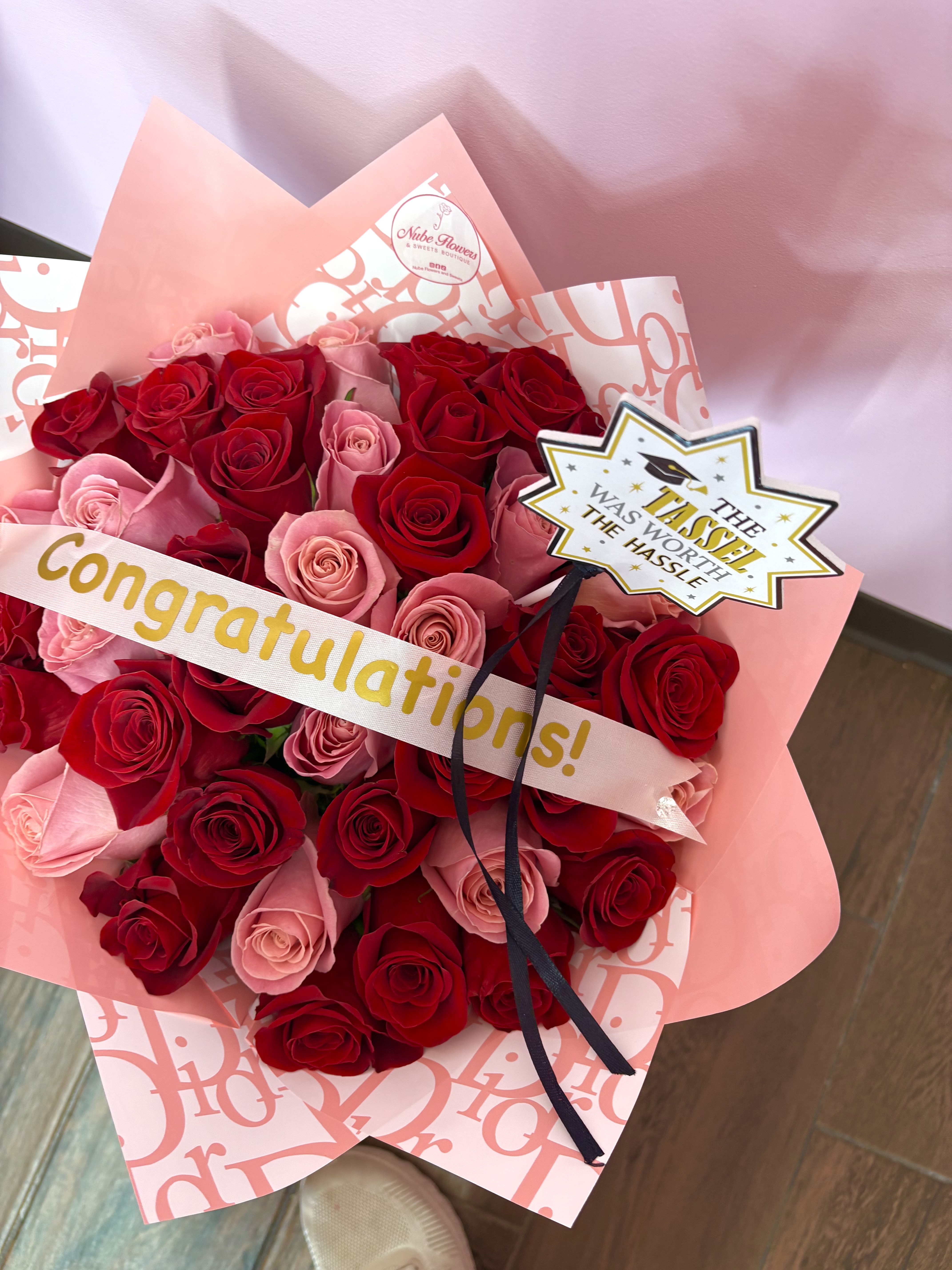 Bouquet of red and pink roses wrapped in pink paper with a congratulations ribbon