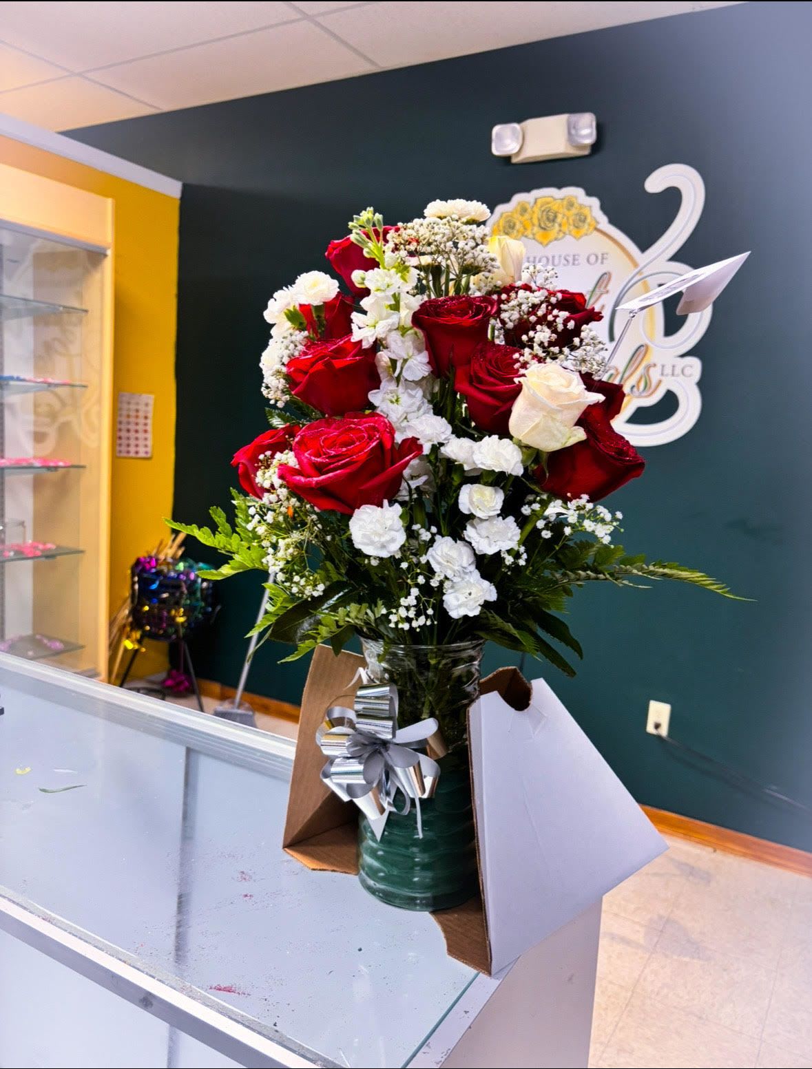 Red and white roses arranged in a glass vase with a silver bow