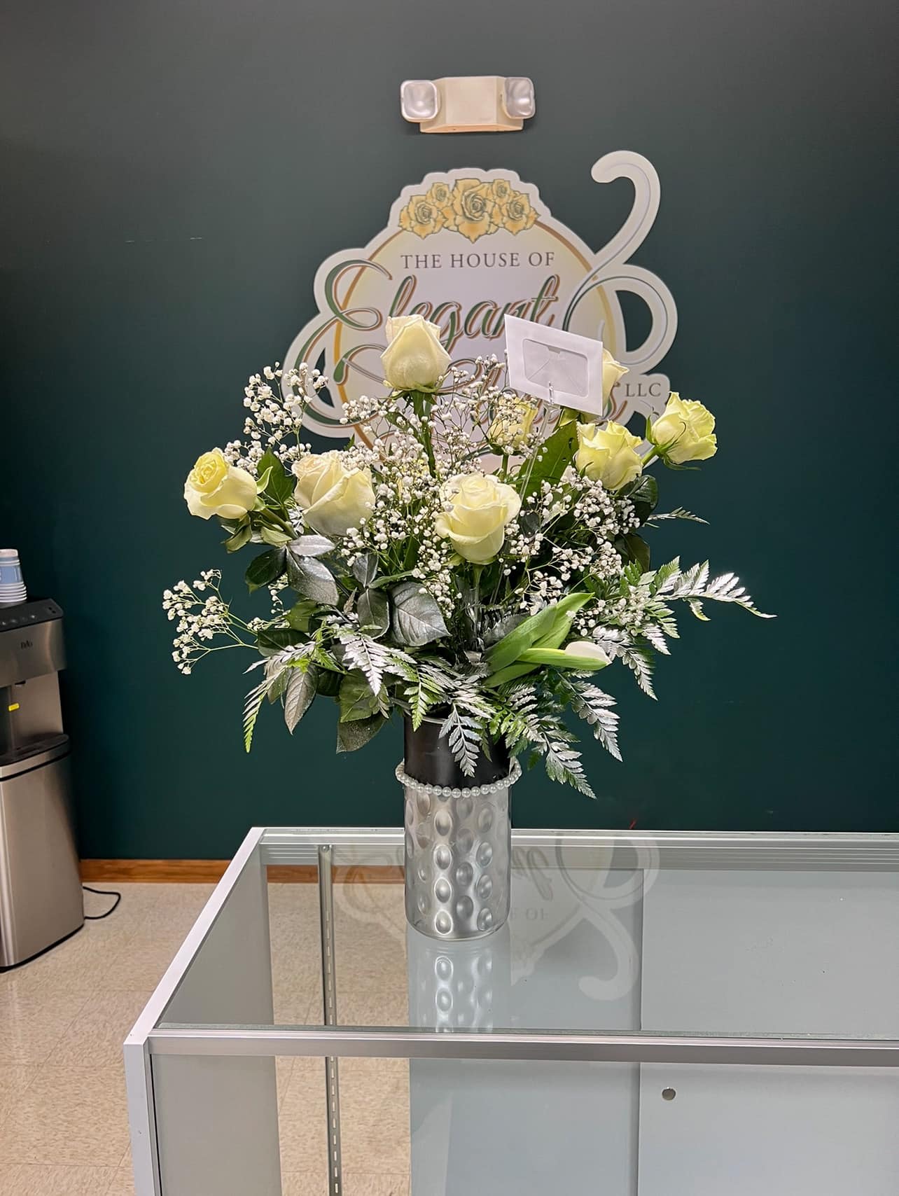 Cream rose arrangement in a silver vase with baby's breath