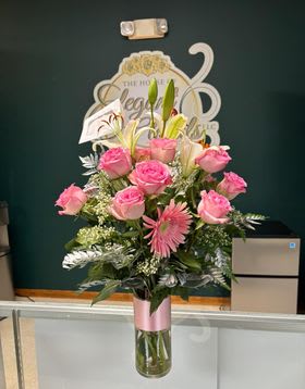 Pink roses and lilies arranged in a tall glass vase