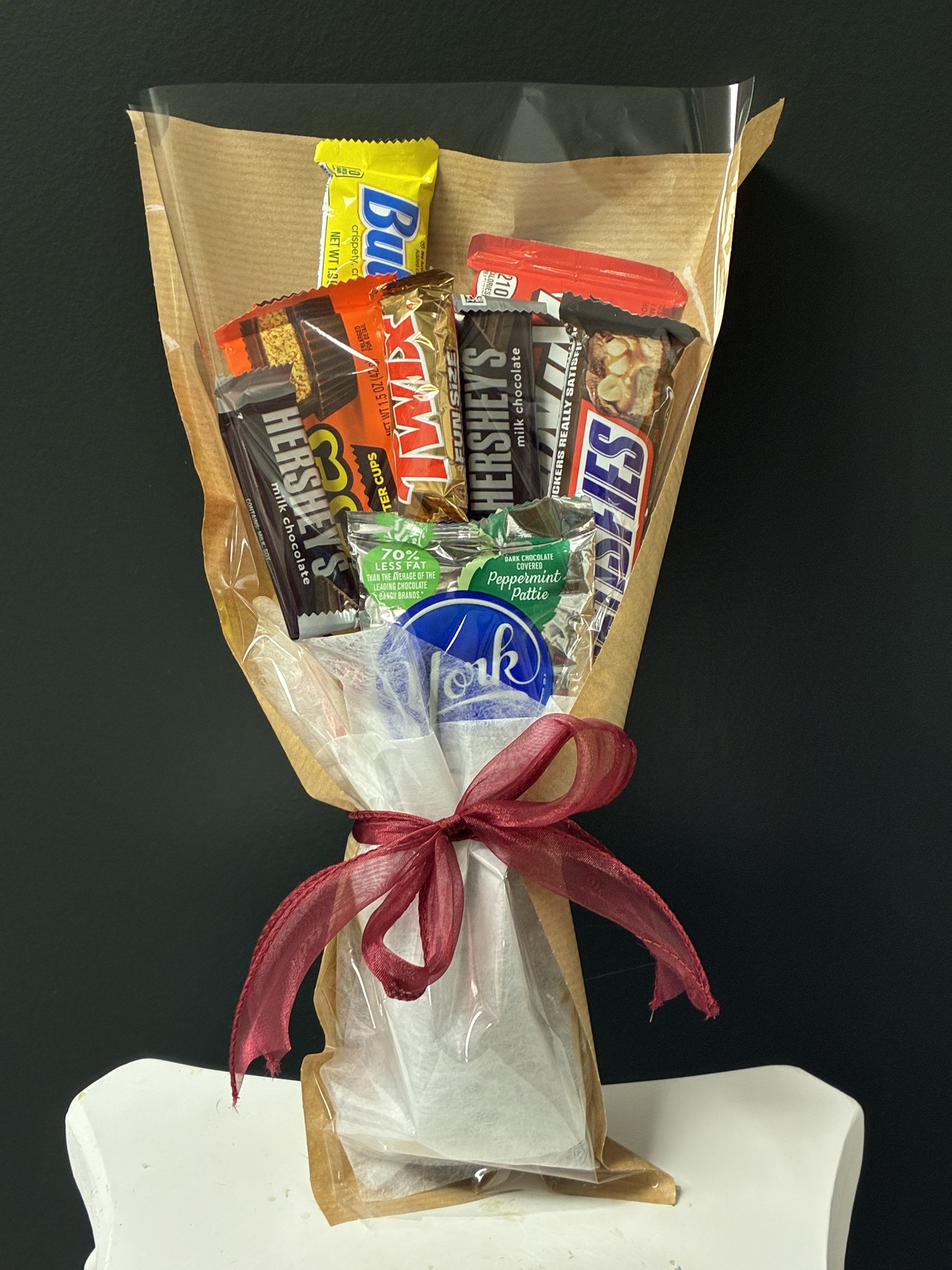 Candy Bar Bouquet - Treat someone special to a bouquet that’s as sweet as it is unique! This handcrafted candy bouquet features 5 full-size candy bars surrounded by 3–5 fun-size candy favorites, beautifully arranged and wrapped for a gift that is sure to make them smile. Perfect for birthdays, graduations, Father’s Day, teacher appreciation, get-well wishes, or just because. No watering required—just enjoy every delicious bite!  Candy varieties may vary based on availability, creating a one-of-a-kind bouquet every time. 