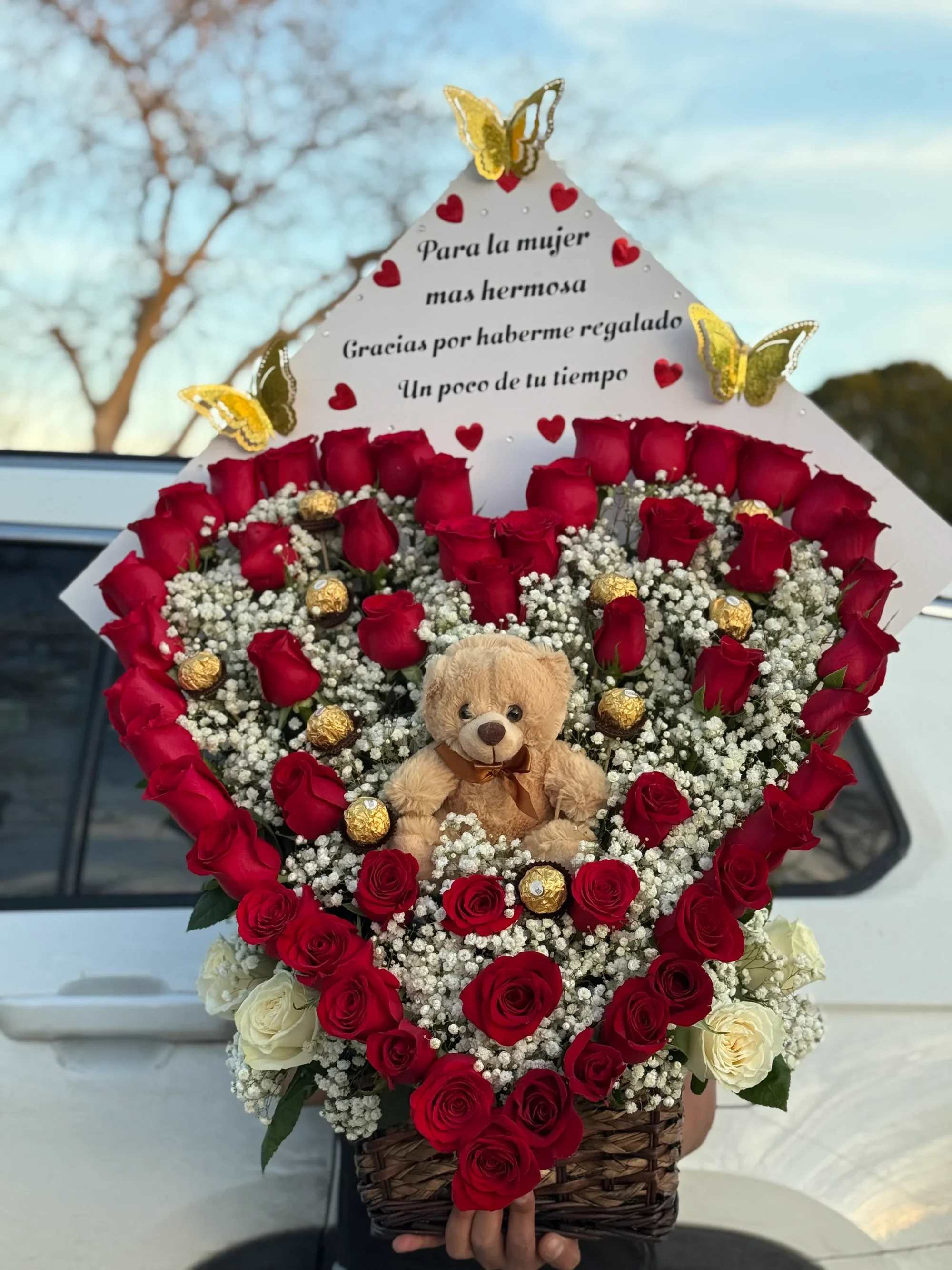Corazón con oso - ️ Arreglo Floral en Forma de Corazón con Peluche y Chocolates   Expresa amor y ternura con este espectacular arreglo floral en forma de corazón. Diseñado con rosas rojas frescas, delicadas flores blancas de complemento y finos chocolates, este detalle es perfecto para sorprender a esa mujer especial.  Al centro incluye un tierno osito de peluche que le da un toque aún más romántico y especial. La parte superior lleva un mensaje emotivo ideal para dedicar en momentos importantes.   Detalles del producto:  Diseño en forma de corazón Rosas rojas frescas Flores blancas de relleno (baby breath) Chocolates tipo Ferrero Peluche decorativo incluido Base tipo canasta resistente Mensaje personalizado en la parte superior    Ideal para aniversario, cumpleaños, San Valentín, propuesta o simplemente para decir “gracias por tu tiempo y tu amor”.   Un regalo elegante, romántico y lleno de significado que dejará una impresión inolvidable.
