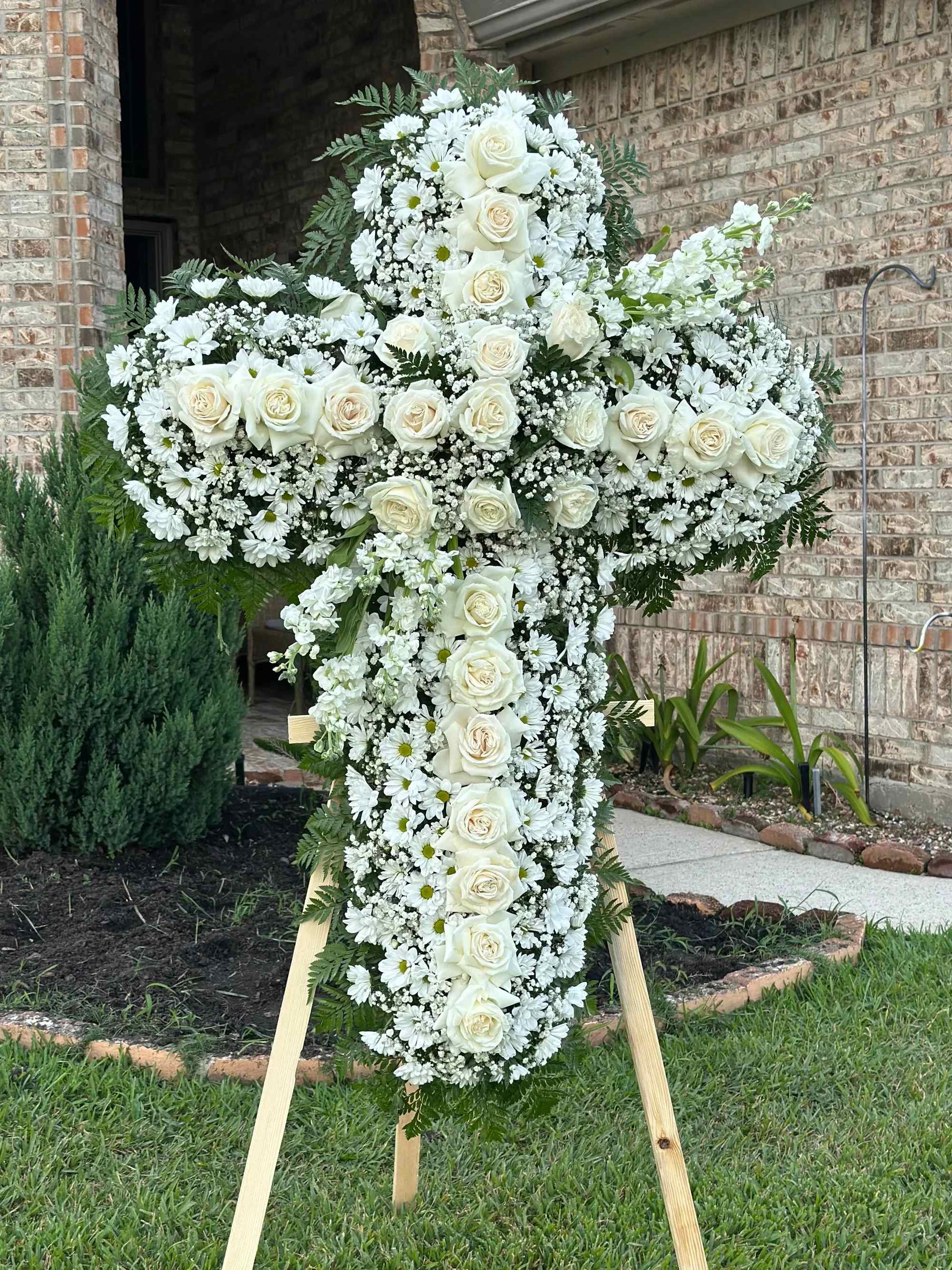 Cruz - ️ Cruz Fúnebre Blanca “Luz y Esperanza”   Honra la memoria de tu ser querido con esta majestuosa cruz floral en tonos blancos, símbolo de pureza, fe y paz eterna.  Diseñada con una delicada combinación de rosas blancas, margaritas, crisantemos y baby breath, cuidadosamente distribuidas para crear un acabado lleno y armonioso. El follaje verde natural realza su elegancia y aporta un contraste sutil y distinguido.   Su diseño en forma de cruz representa esperanza y consuelo, convirtiéndola en un tributo significativo para momentos de despedida.   Detalles del producto:   Rosas blancas frescas Margaritas blancas Crisantemos blancos Flores de relleno (baby breath) Follaje verde natural Base de madera incluida   ️ Ideal para funerales, velorios y ceremonias religiosas.   Un arreglo solemne y elegante que expresa respeto, amor y acompañamiento.