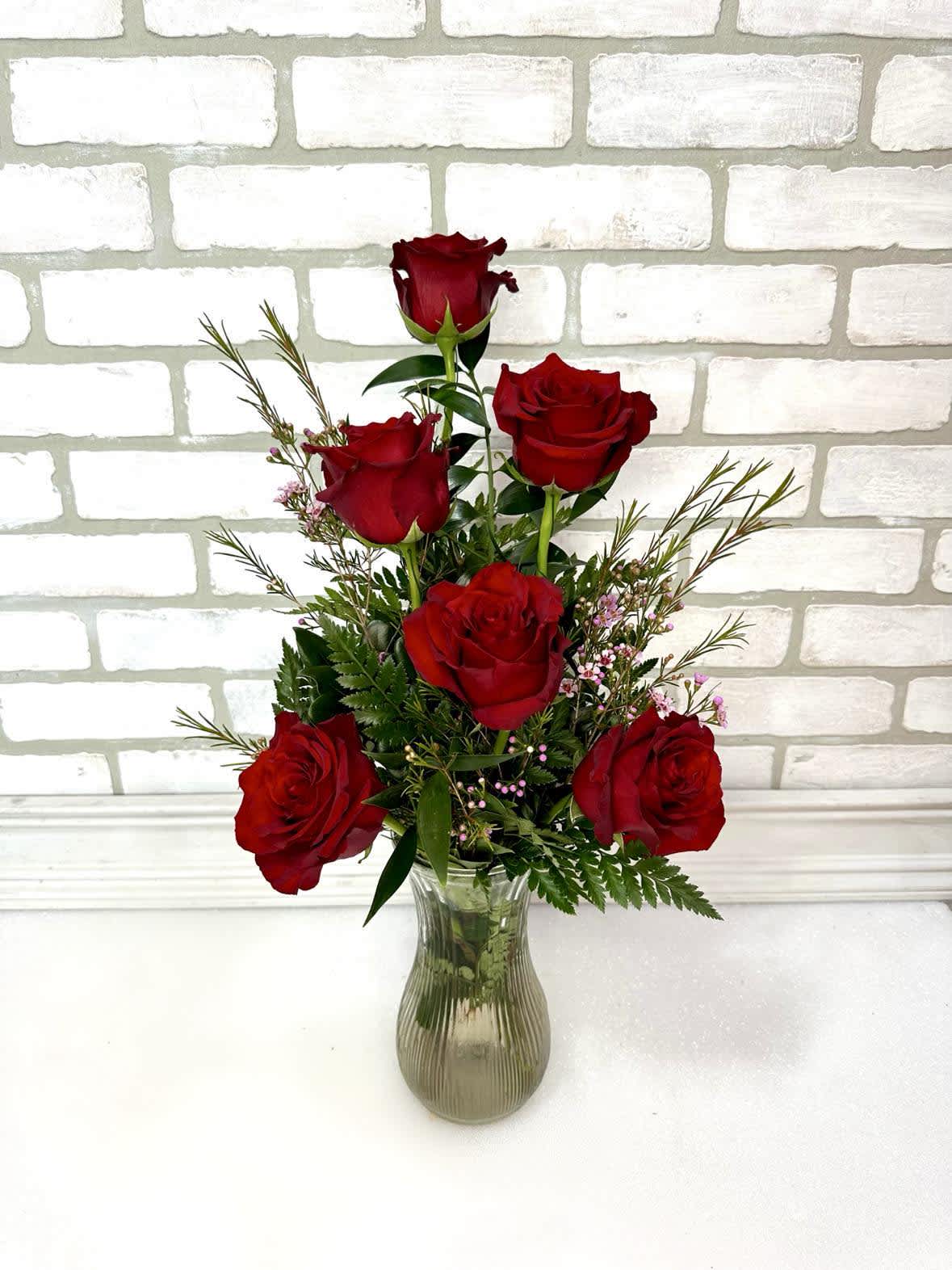 Red roses arranged in a clear glass vase