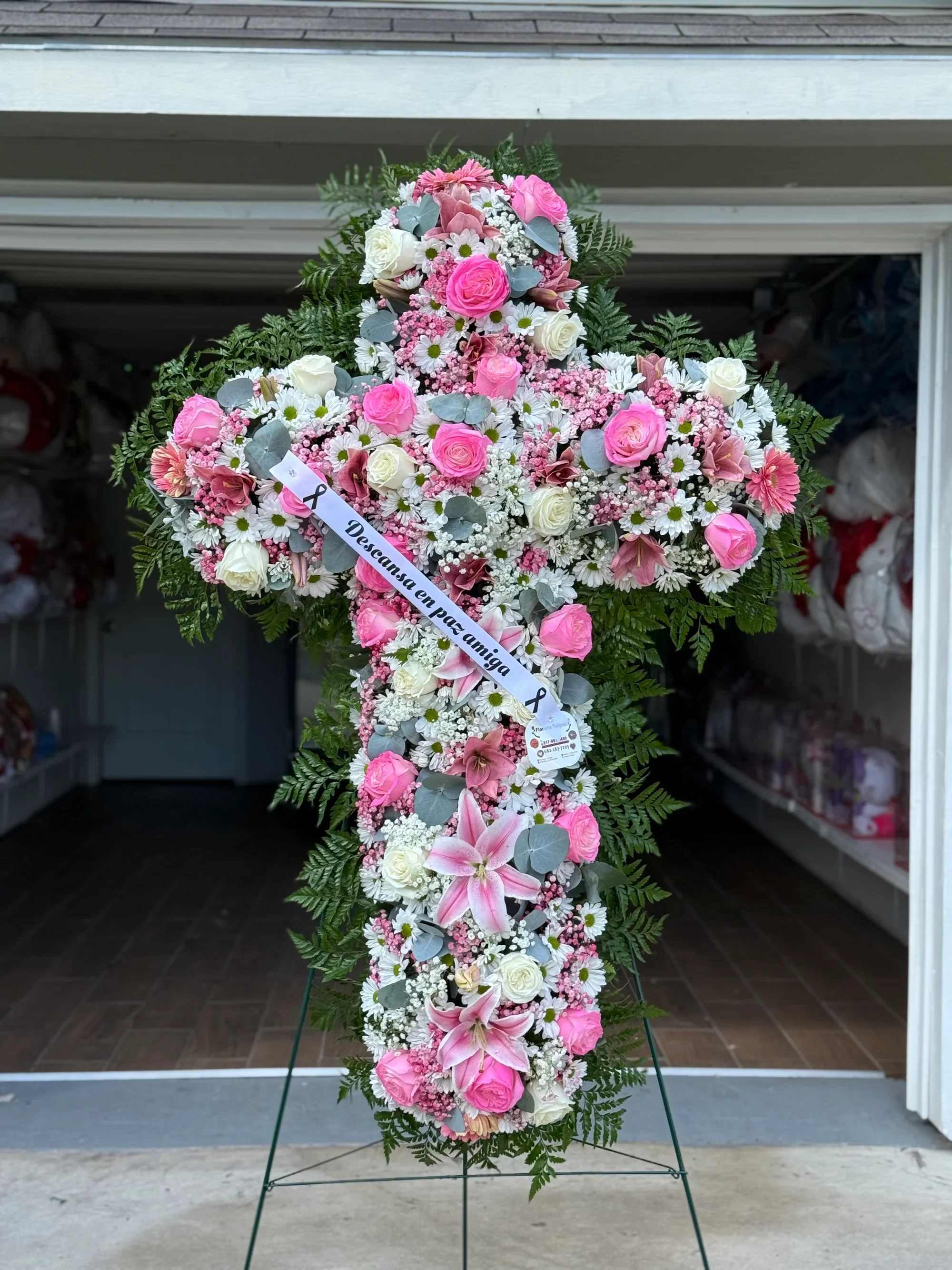 Funeral Cruz -  Cruz Floral Fúnebre en Tonos Rosa y Blanco – Homenaje de Amor   Honra la memoria de tu ser querido con esta hermosa cruz floral elaborada con flores frescas en delicados tonos rosa y blanco. Diseñada cuidadosamente para transmitir paz, amor y un último mensaje lleno de cariño.  Este arreglo combina rosas rosadas y blancas, lirios, margaritas y finos follajes verdes que realzan su elegancia y solemnidad. Incluye listón personalizado con mensaje conmemorativo.   Detalles del arreglo:  Diseño en forma de cruz Rosas frescas en tonos rosa y blanco Lirios y flores complementarias Follaje verde natural Listón con mensaje personalizado Base con soporte incluido    Ideal para:  Servicios funerarios Velorios Misas conmemorativas Homenajes especiales  Un tributo floral elegante y significativo que expresa respeto, amor y despedida eterna.  Contáctanos para personalizar el mensaje del listón y acompañar tu detalle con palabras especiales.