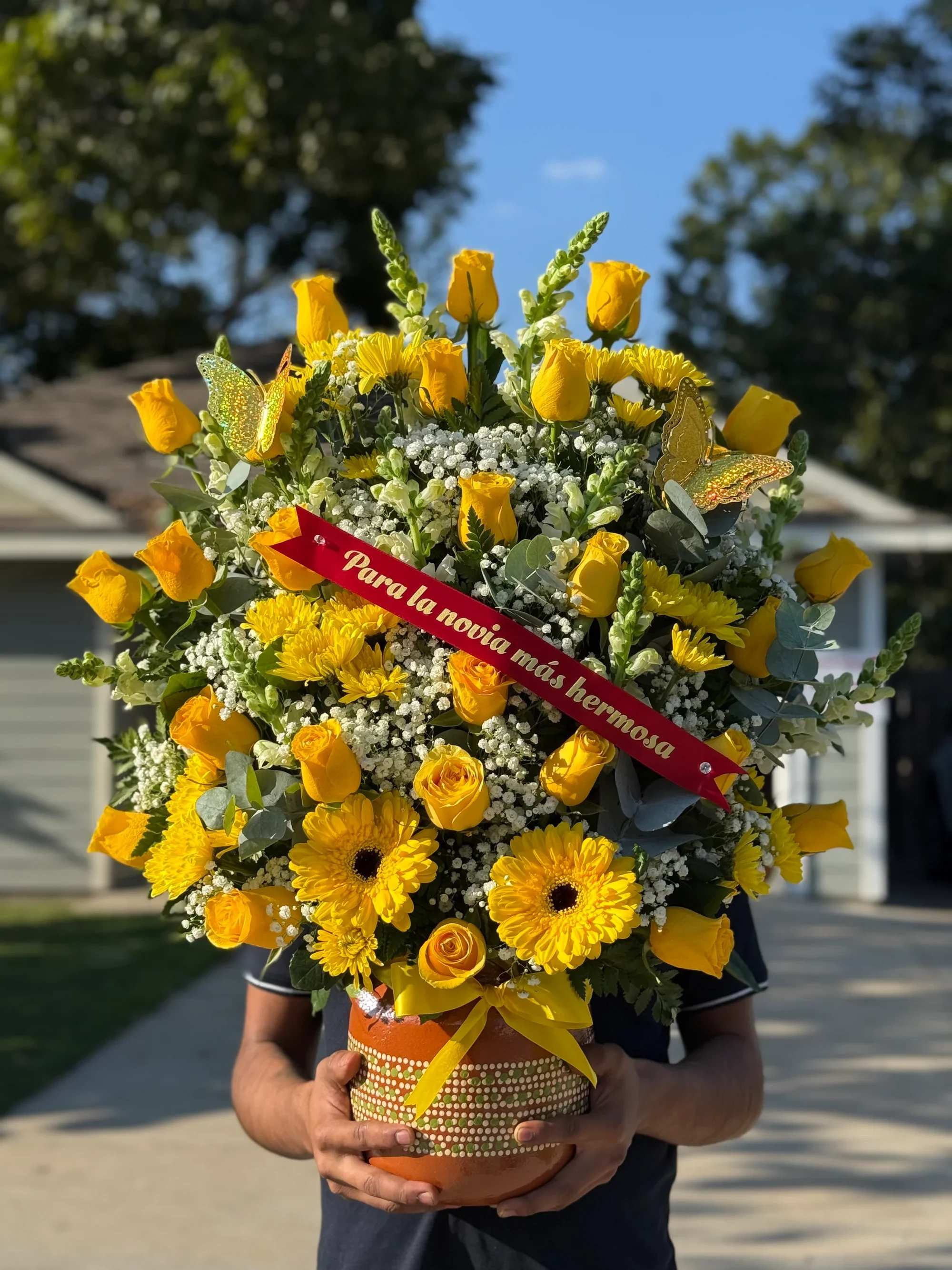 Ollita de flores surtidas -  Arreglo Premium “Para la Novia Más Hermosa”   Sorprende con un detalle radiante y lleno de vida. Este espectacular arreglo combina la elegancia de las rosas amarillas con la alegría de los girasoles y la delicadeza de las flores blancas, creando una composición vibrante y romántica.   Incluye:   Rosas amarillas frescas de alta calidad  Girasoles y gerberas que aportan luz y energía  Flores blancas tipo baby’s breath para dar volumen y delicadeza  Follaje verde natural y detalles decorativos  Mariposas decorativas elegantes  Listón rojo con mensaje: “Para la novia más hermosa”  Base de cerámica decorativa incluida   Ideal para:  Aniversarios Cumpleaños Sorpresas románticas Pedidas especiales Celebraciones importantes   Un arreglo diseñado para transmitir alegría, amor y admiración en cada detalle. Perfecto para iluminar su día y hacerla sentir única.   Entregas disponibles.  Haz tu pedido hoy y regala una experiencia inolvidable.