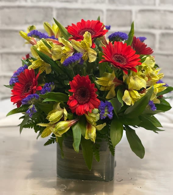 Bouquet of red gerbera daisies and yellow alstroemeria in a glass vase
