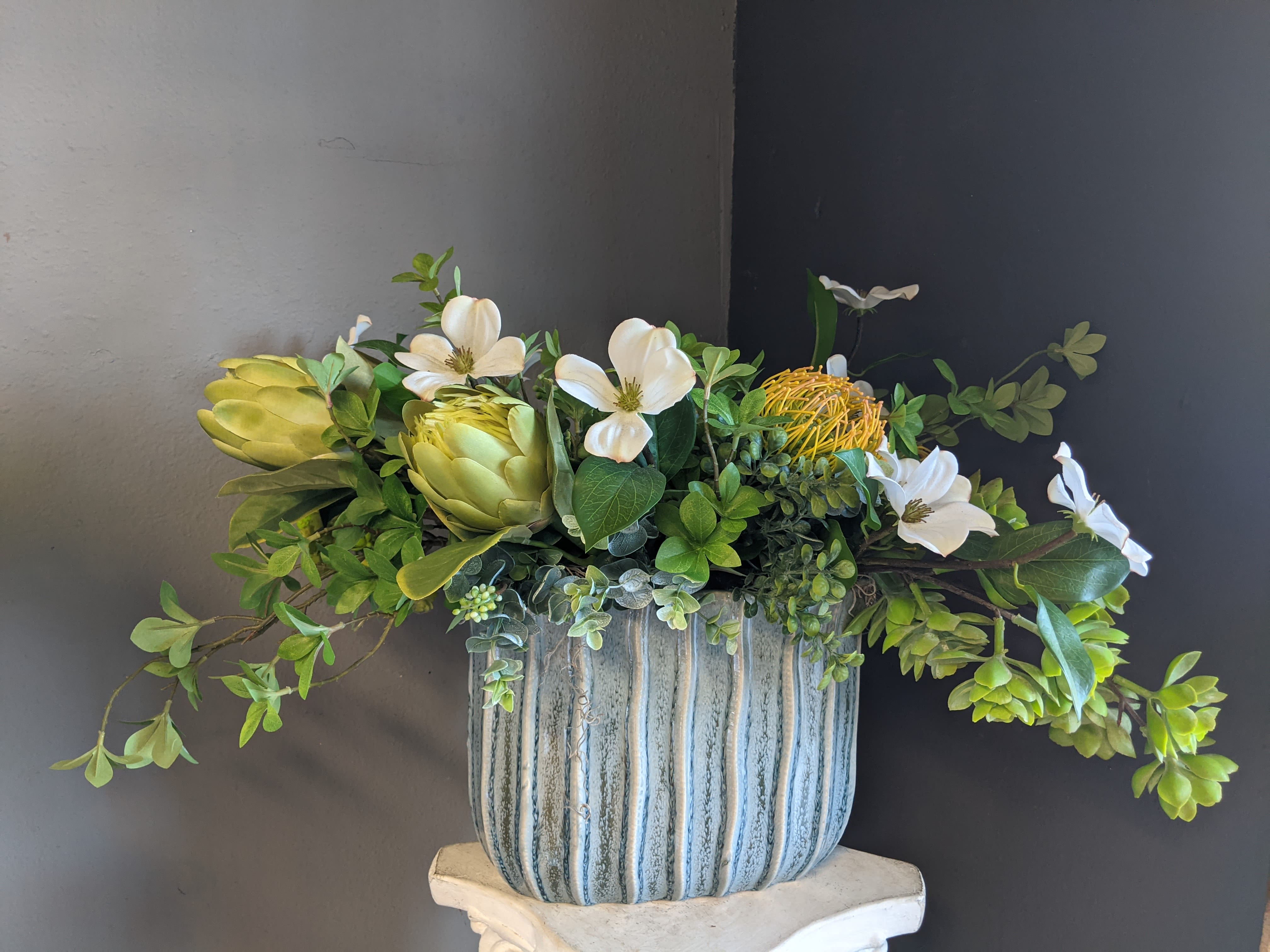 Arrangement of white flowers and green succulents in a striped ceramic pot