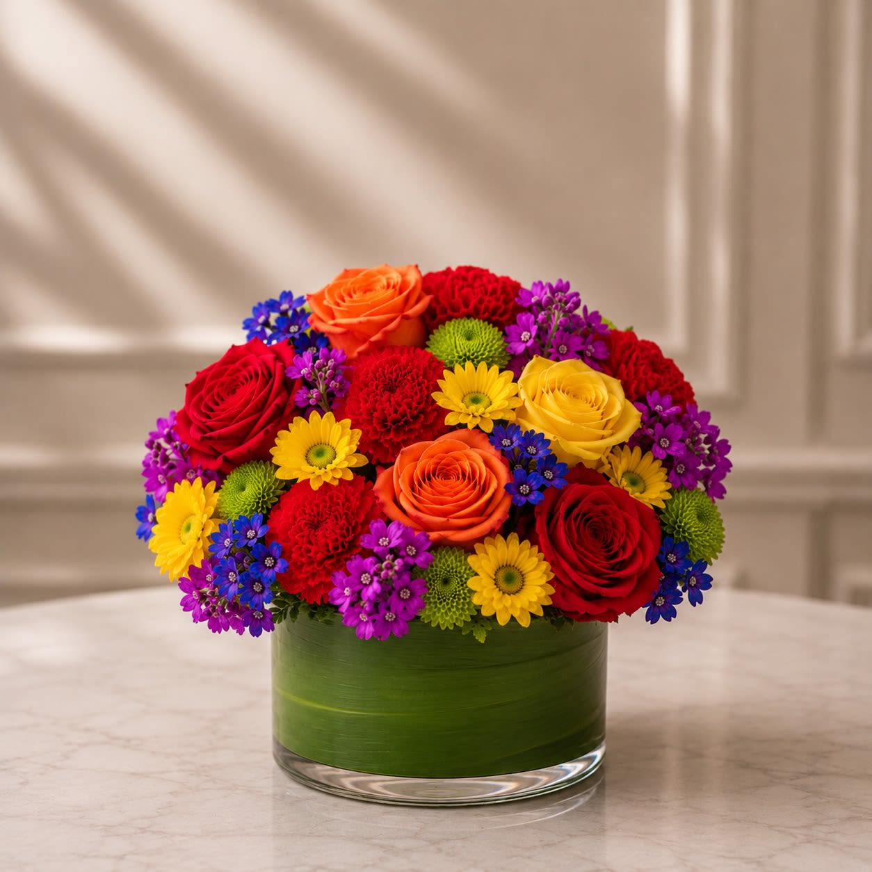 Love in Full Color - Celebrate love, authenticity, and self-expression with Love in Full Color™, a vibrant floral arrangement inspired by the beauty and diversity of the Pride community. Designed in a modern leaf-lined glass cylinder vase, this joyful arrangement features a stunning blend of premium roses, carnations, daisy chrysanthemums, green button mums, and seasonal accent blooms arranged in a rich spectrum of colors.  Each bloom represents the spirit of Pride—love, courage, inclusion, hope, and unity. The combination of vivid reds, oranges, yellows, greens, blues, and purples creates a cheerful and meaningful display that brightens any home, office, celebration, or special event.  Whether you’re celebrating Pride Month, honoring a loved one, supporting the LGBTQ+ community, or sending a message of love and acceptance, Love in Full Color™ is designed to make a lasting impression. Handcrafted by our floral designers using the freshest flowers available, each arrangement is unique while maintaining the vibrant rainbow-inspired palette that makes this design so special.  Flower varieties may vary based on seasonal availability while preserving the overall color scheme, style, and premium presentation.