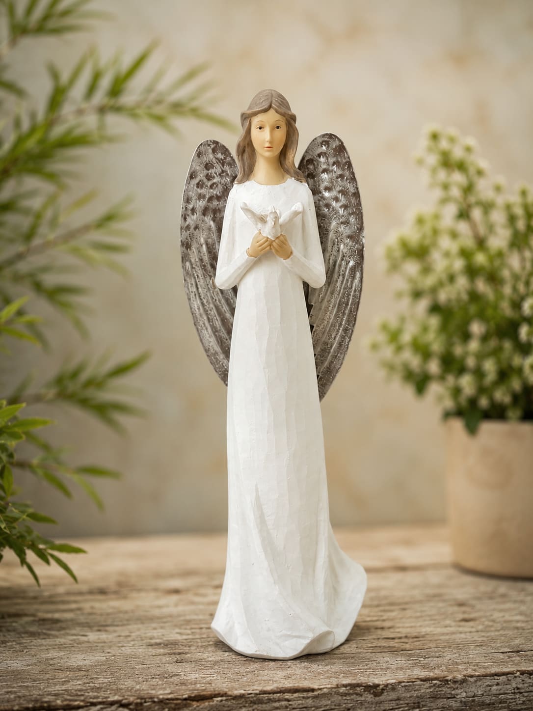 11.5” Dove of Peace Angel Figuine - Offer comfort, hope, and lasting remembrance with the Dove of Peace Angel Figurine. Standing approximately 11.5 inches tall, this elegant angel holds a dove, a timeless symbol of peace, faith, love, and encouragement. Beautifully detailed and designed to inspire comfort, this keepsake serves as a meaningful reminder that treasured memories remain close to the heart.  The Standard version includes the angel figurine by itself, making it a thoughtful keepsake for the home, office, memorial display, remembrance table, or faith-inspired décor.  The Deluxe version features the angel designed within a fresh floral arrangement, combining the beauty of flowers with a keepsake that can be cherished long after the blooms have faded.  The Premium version showcases the angel within a larger floral tribute, creating a striking display suitable for memorial services, visitations, celebrations of life, and special remembrance occasions.  Perfect for sympathy, bereavement, memorial gifts, encouragement, faith-based gifts, funeral services, celebration of life gatherings, anniversaries of loss, and lasting home décor.  Because floral designs are individually created, flower varieties, containers, and accents may vary based on availability. The overall style, theme, and presentation of Dove of Peace Angel Figurine will be maintained.