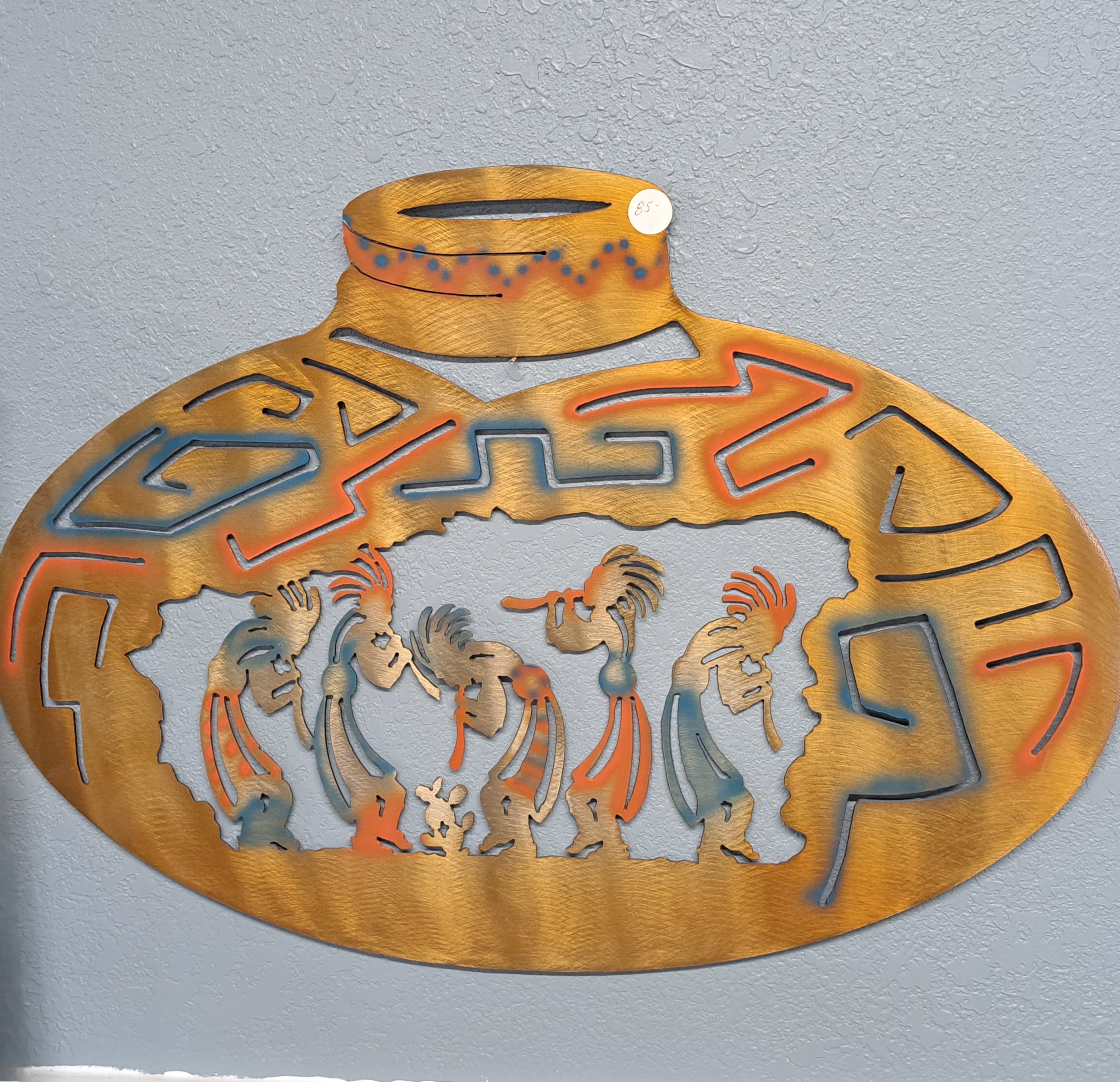 Decorative metal wall art with stylized figures in an oval frame