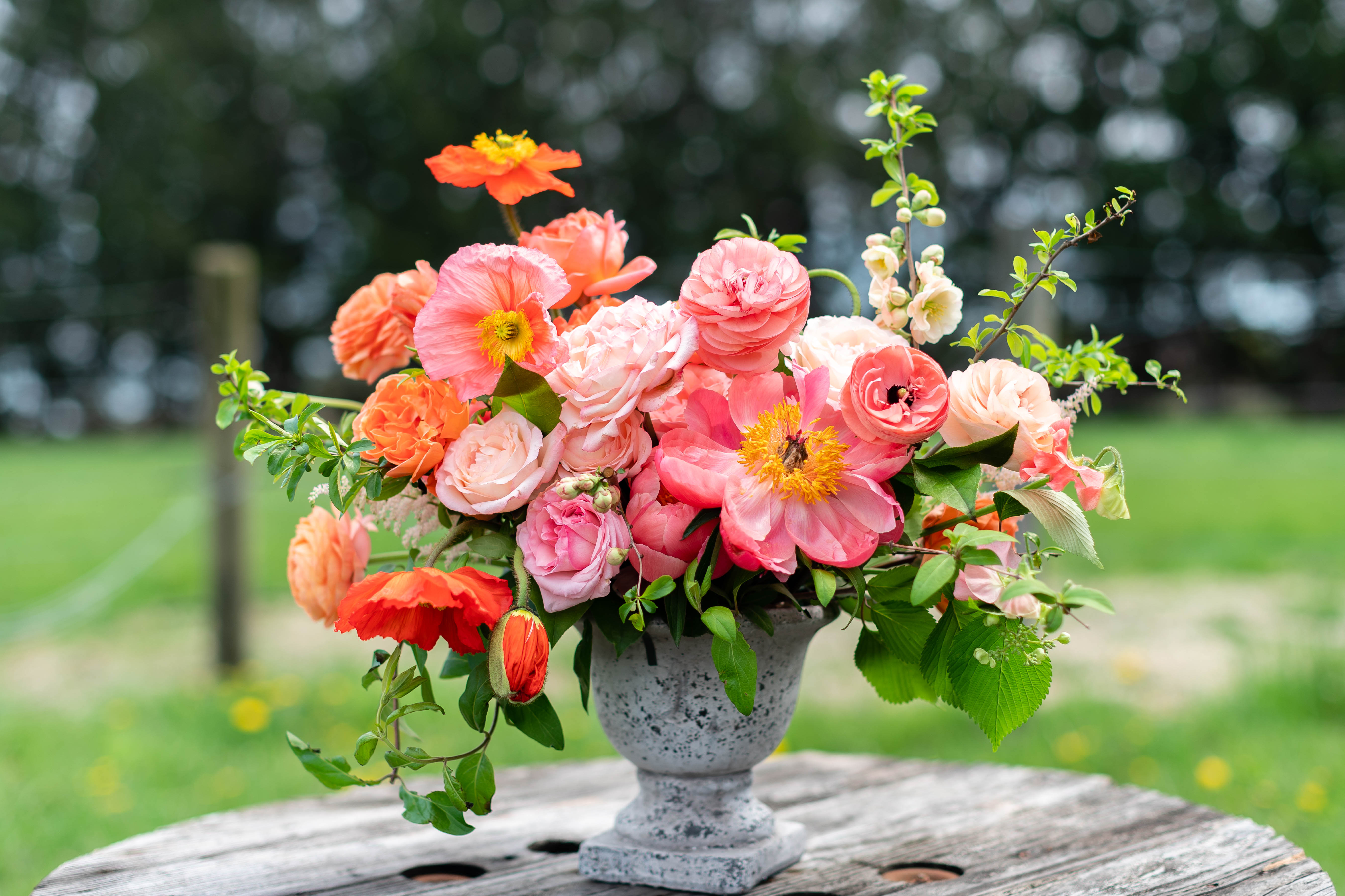 Pink and coral flower arrangement in a gray urn vase