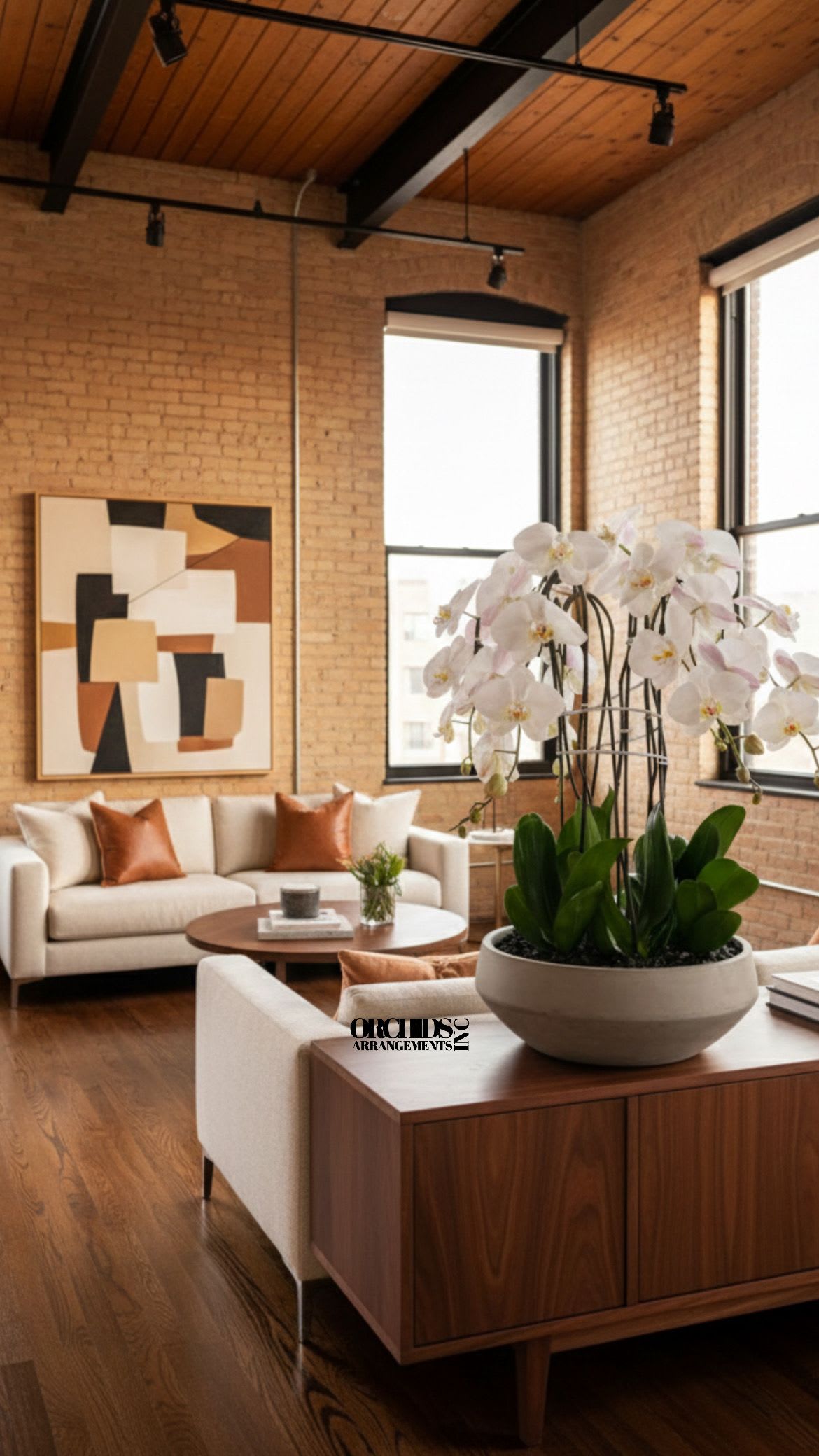 White orchids in a round planter on a wooden table