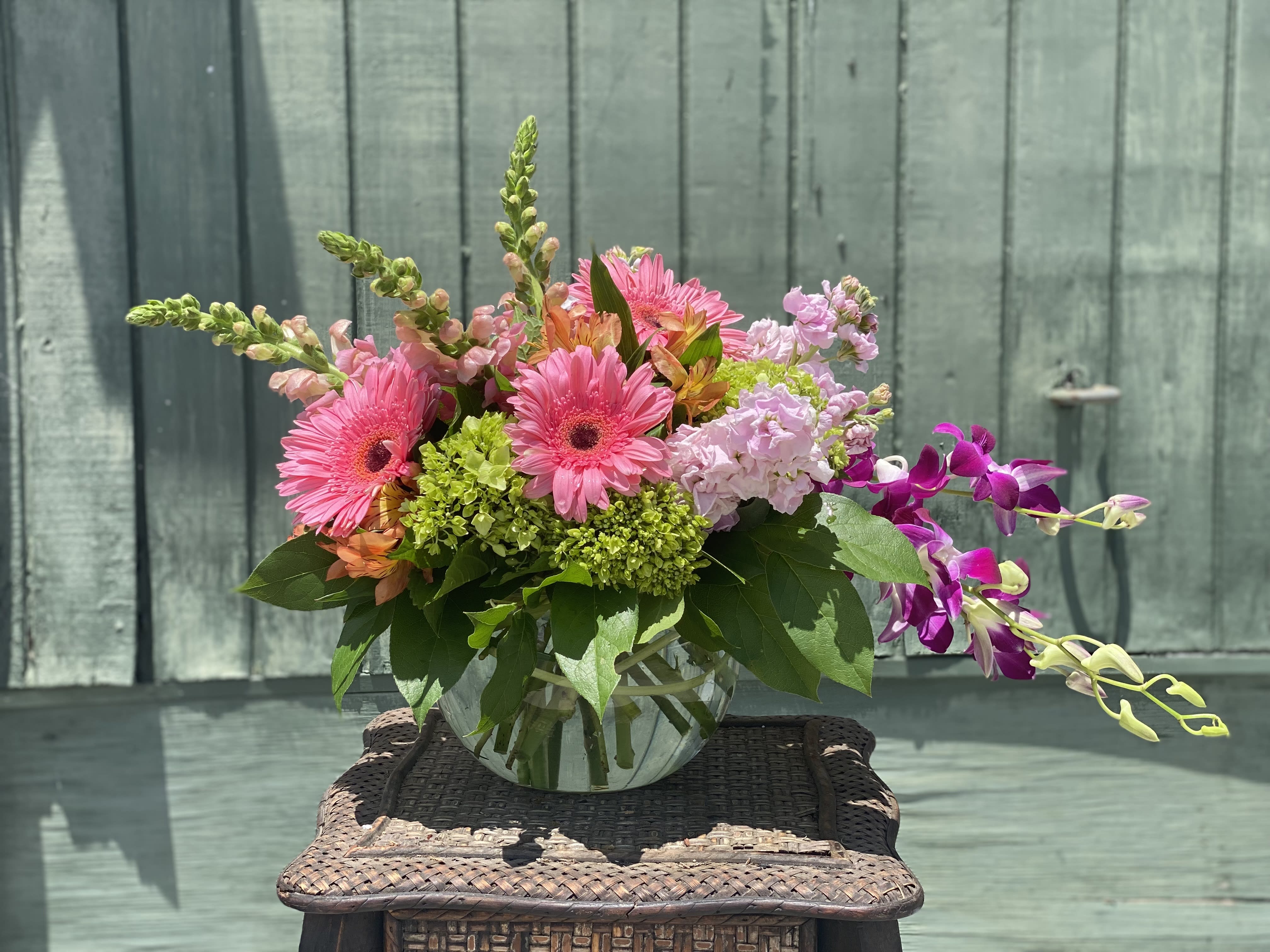 Pink gerbera daisies and orchids in a glass vase