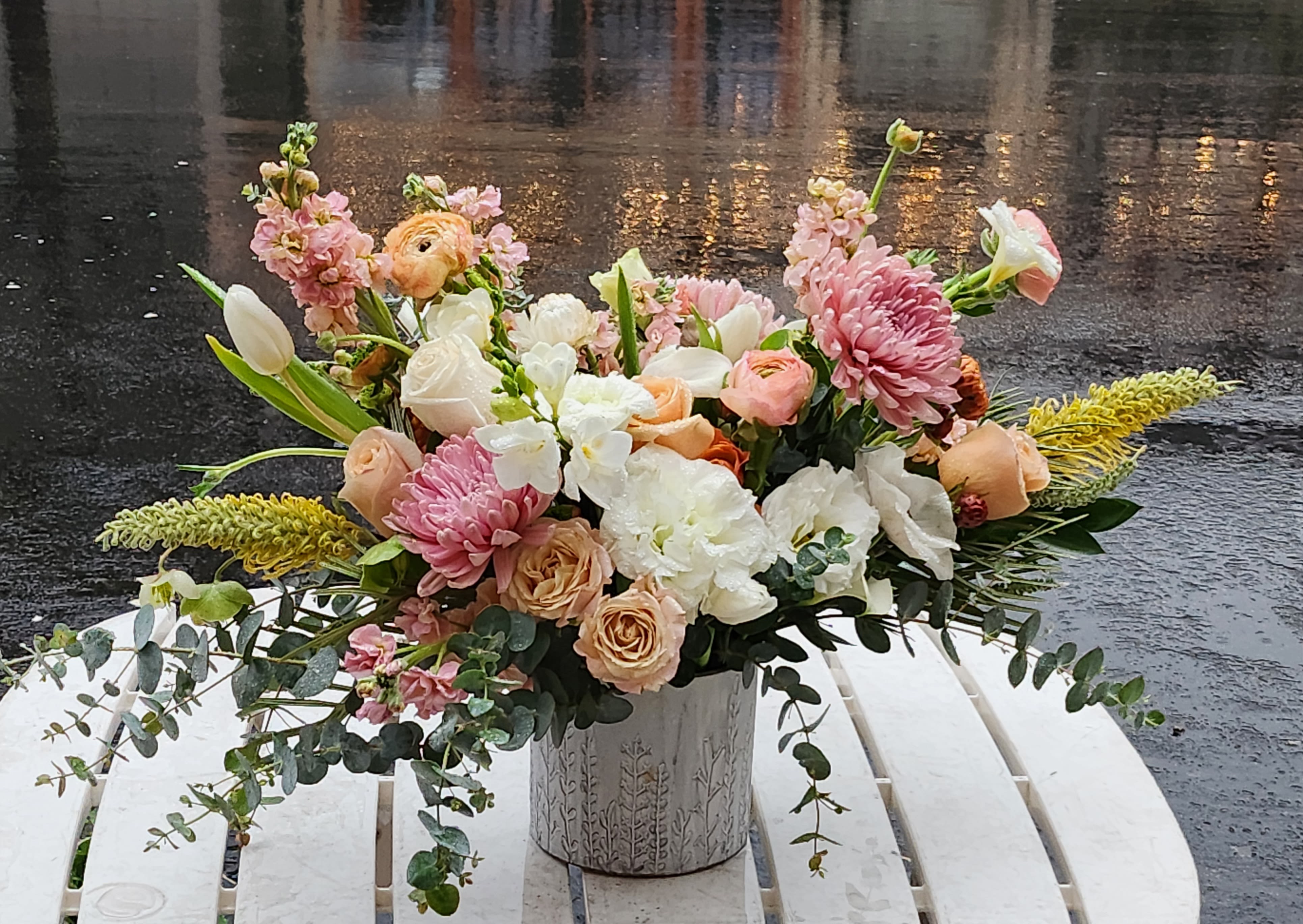 Mixed pastel bouquet in a decorative metal vase on a white table