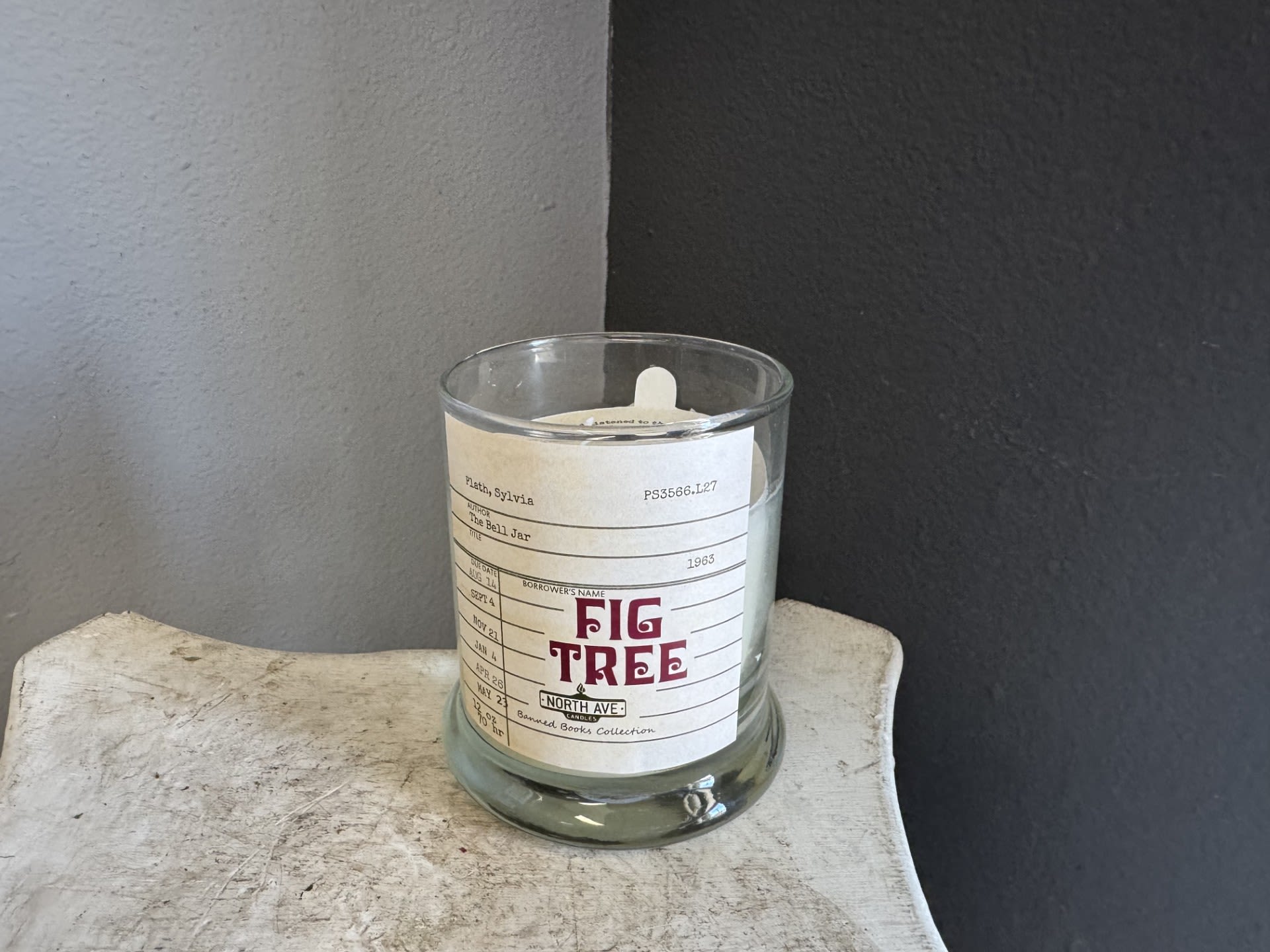 A glass candle jar with a Fig Tree label sits on a small table.