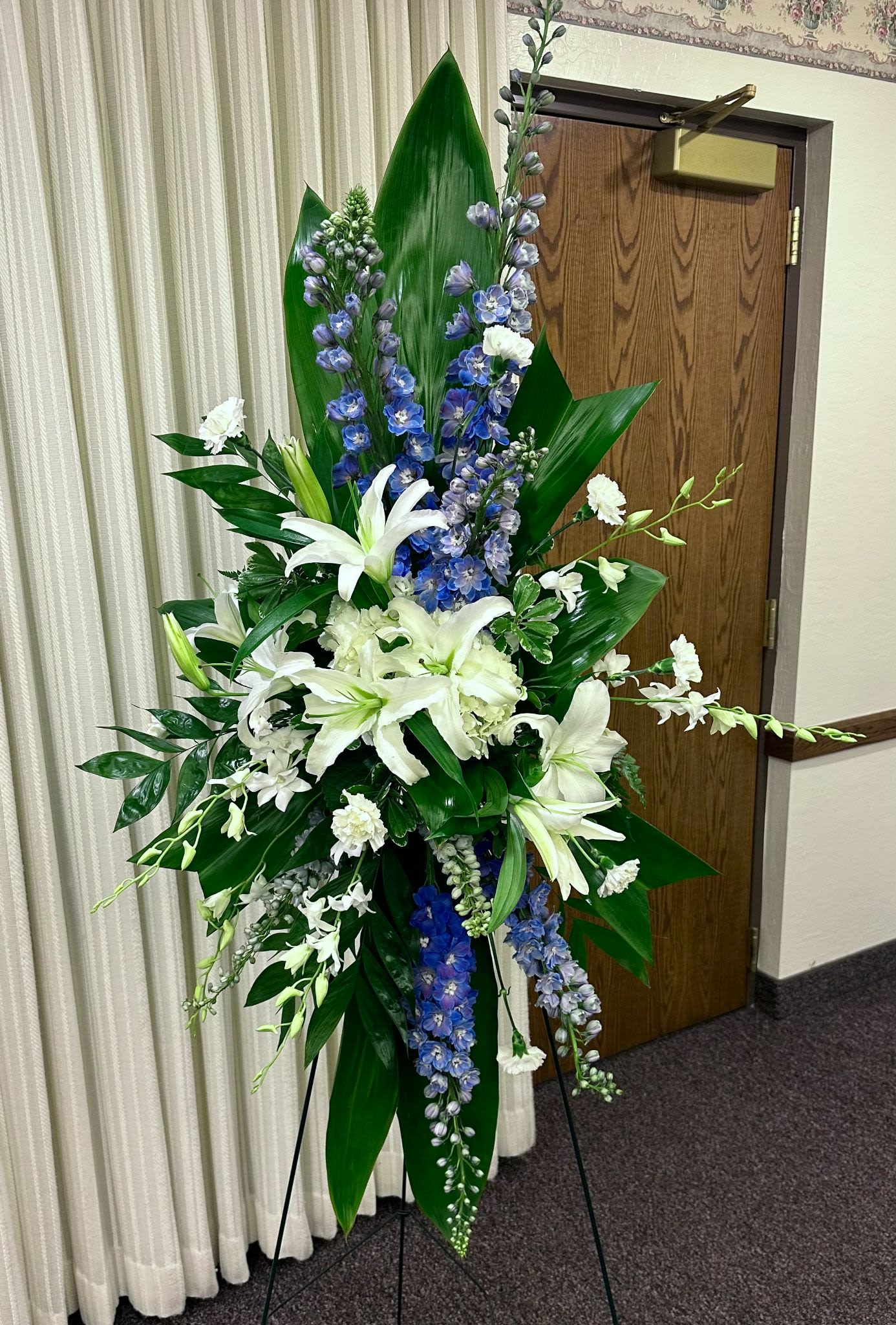 Tall white and blue floral standing spray on an easel