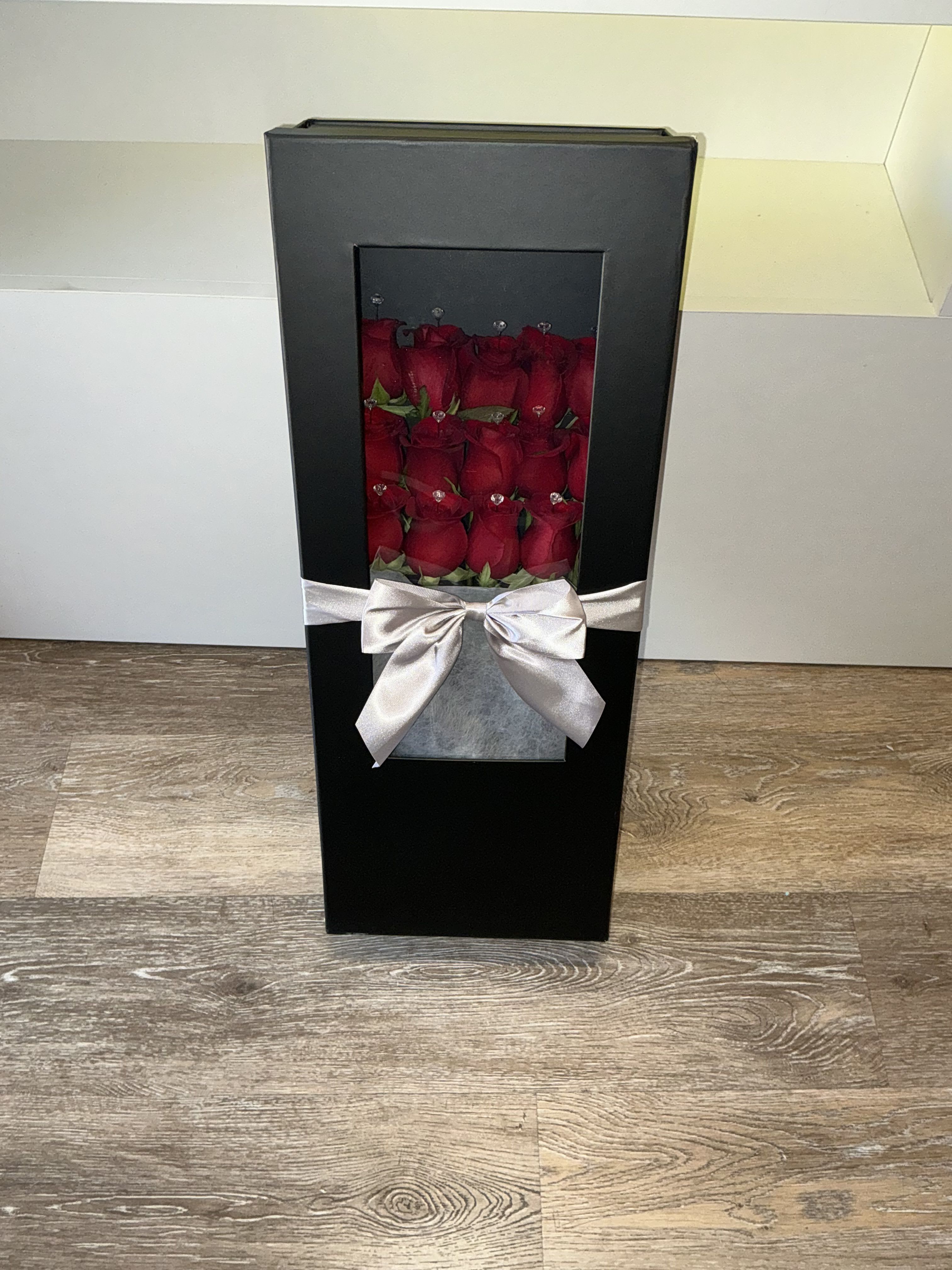 Black gift box with red roses and a silver ribbon bow