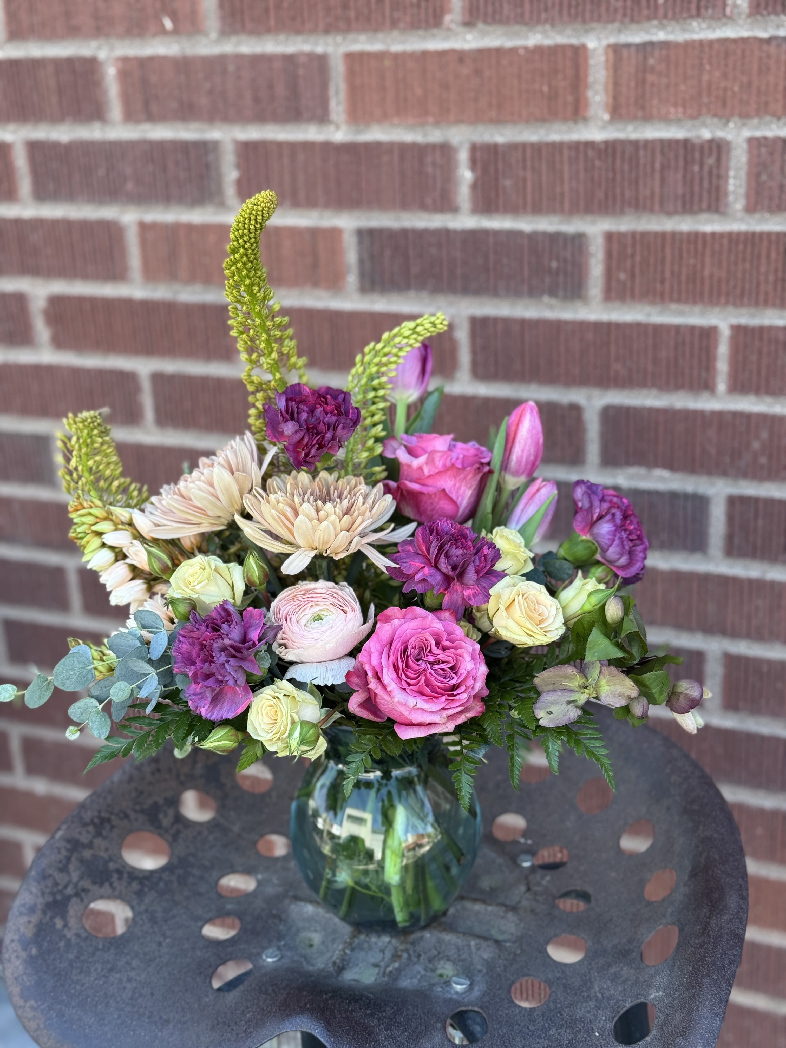 WEEKLY DROP! - LIMITED EDITION - Velvet Meadow - Step into a world of rich, romantic textures. This masterfully crafted arrangement is a bold celebration of seasonal beauty, balancing deep jewel tones with soft, cream accents. Majestic foxtail lilies add height &amp; drama, delicate ranunculus offers a romantic focal point &amp; rich purple accents in deep violet carnations and magenta garden roses ground the palette with luxury.