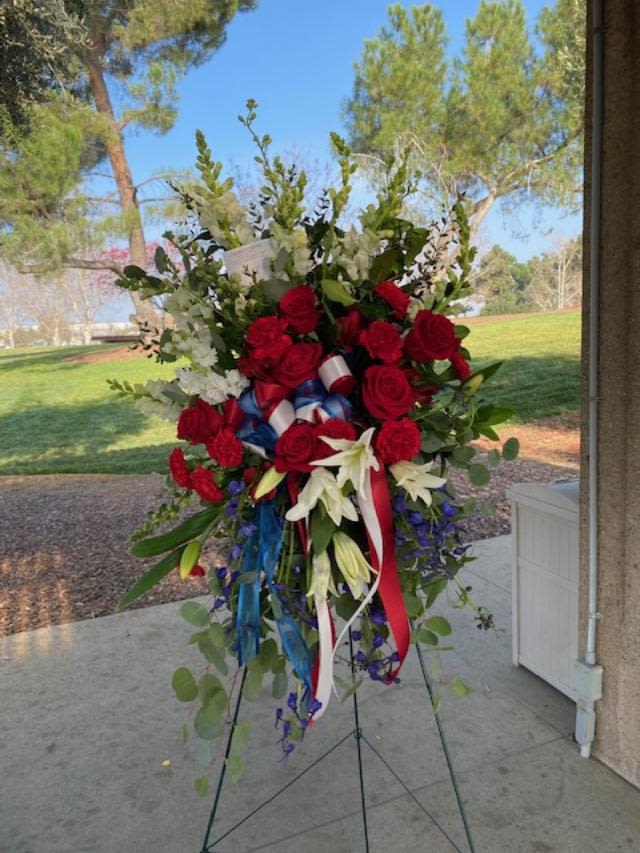Veteran's Honor Standing Spray - This Standing spray is designed in patriotic colors of red white and blue to show thanks and give honor to our service men and women. Flowers may include white snapdragons, red roses, white lilies, and blue delphinium. Substitutions may be necessary based on product availability. 