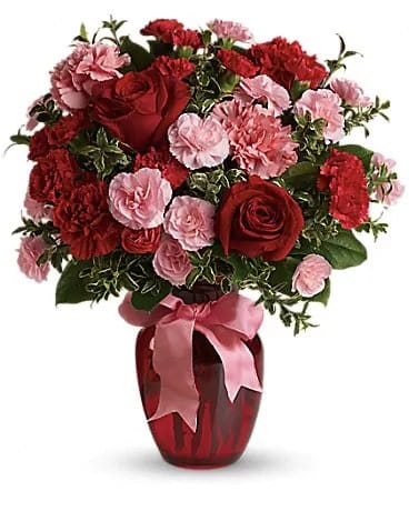 Red roses and pink carnations in a red vase with a pink ribbon