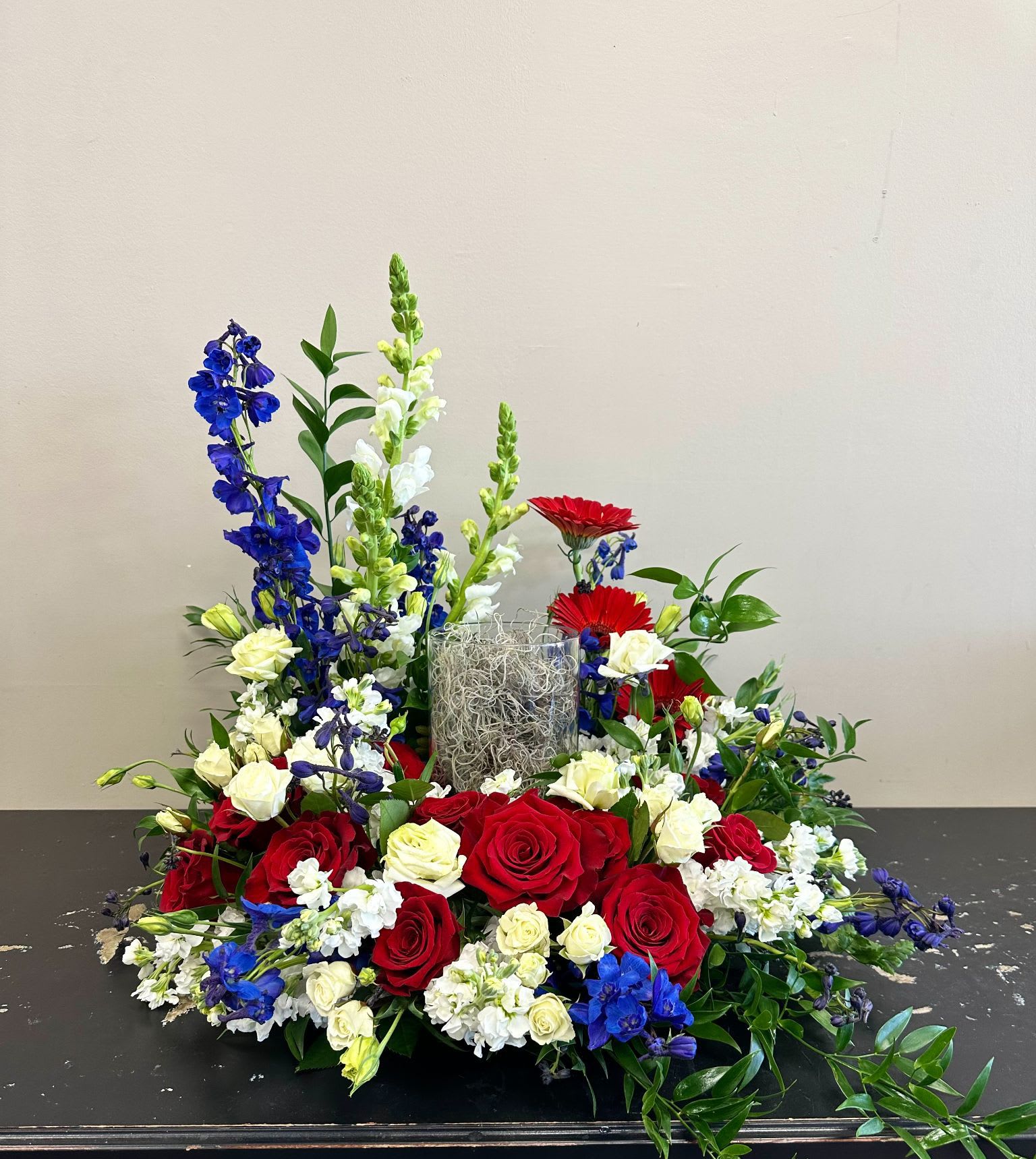 Red and white roses with blue and white flowers in a low centerpiece