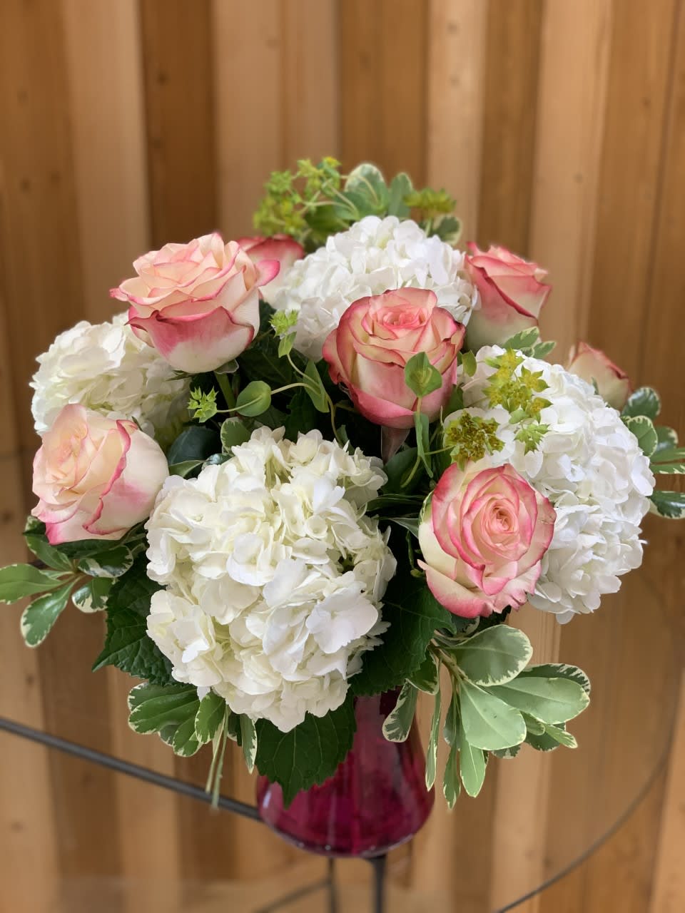 Pink-edged roses and white hydrangeas in a glass vase