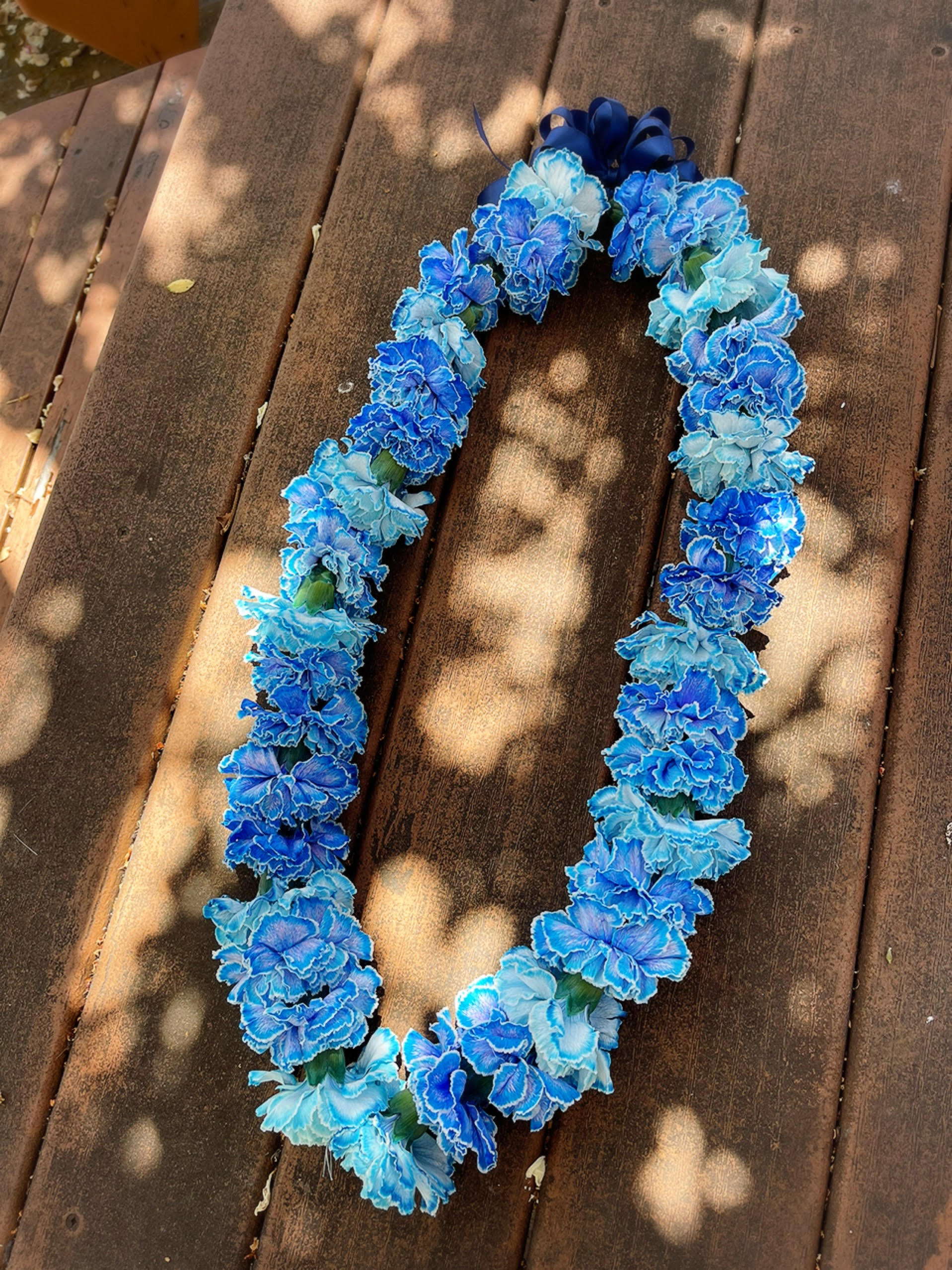 Blue and light blue flower lei on a wooden surface