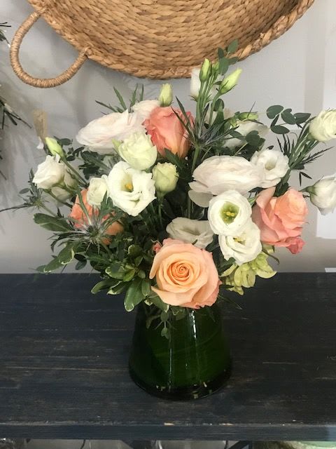 Mixed bouquet of peach and white flowers in a dark glass vase