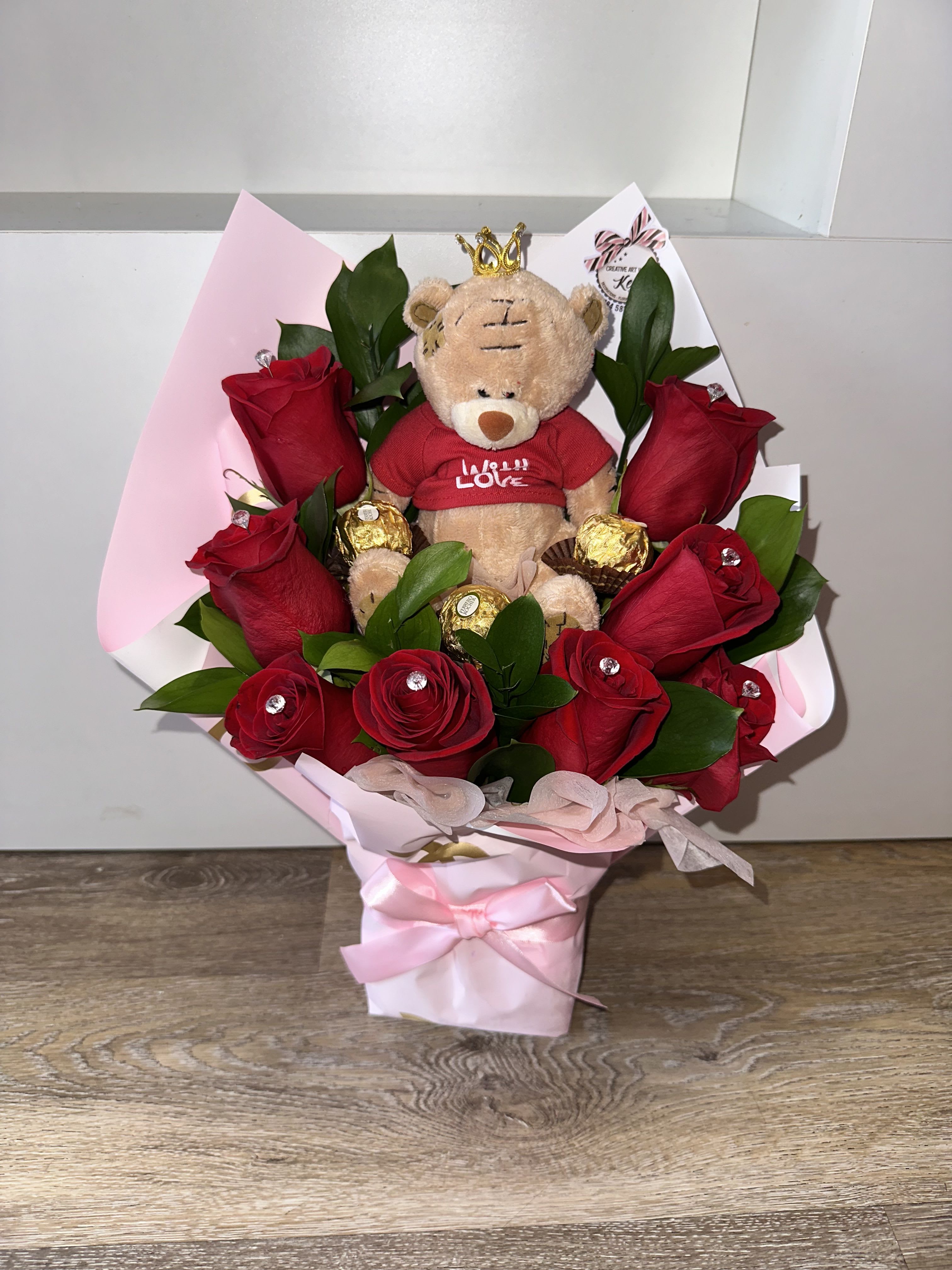 Bouquet of red roses with a teddy bear and chocolates in pink wrapping