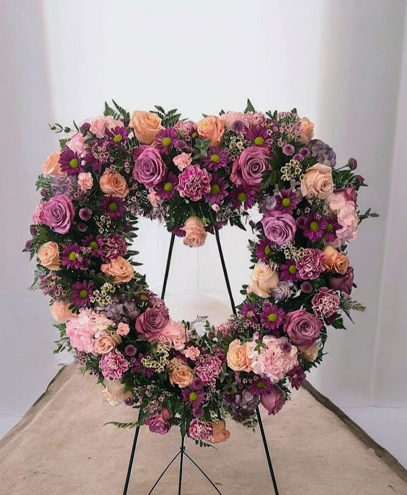 Forever in Bloom - A lush heart-shaped sympathy tribute in soft lavender, blush, and pink blooms, designed to honor a cherished life with beauty and love.