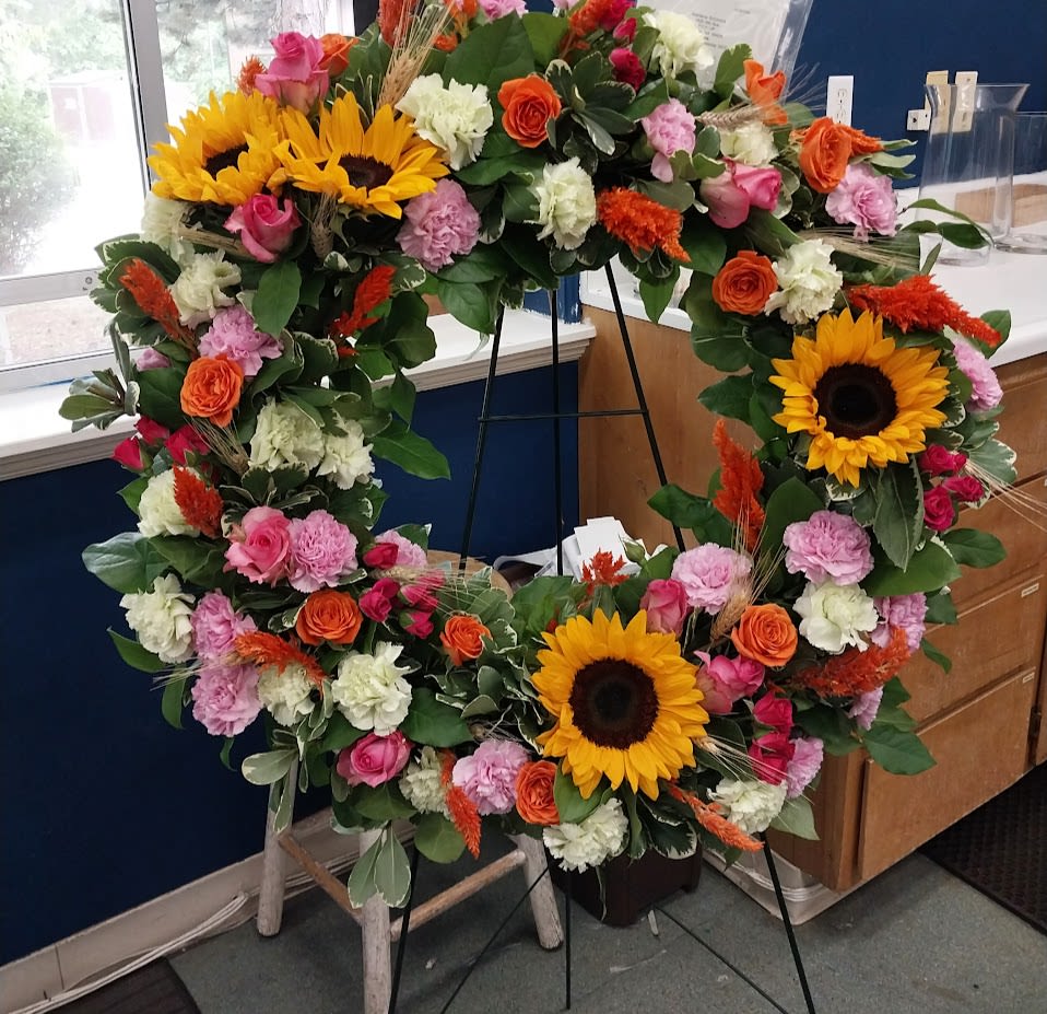 Brightest Memories - A vibrant sunflower wreath accented with roses, carnations, and seasonal blooms. 