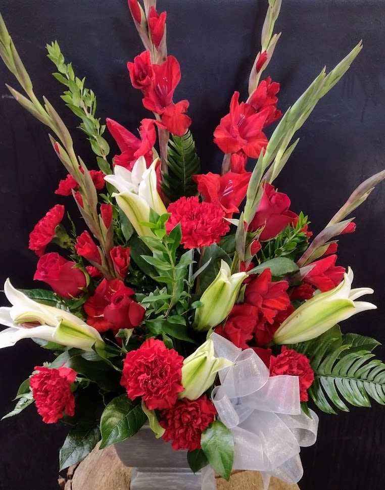 A Legacy of Love - A striking tribute featuring red gladiolus, white lilies, and lush greenery.