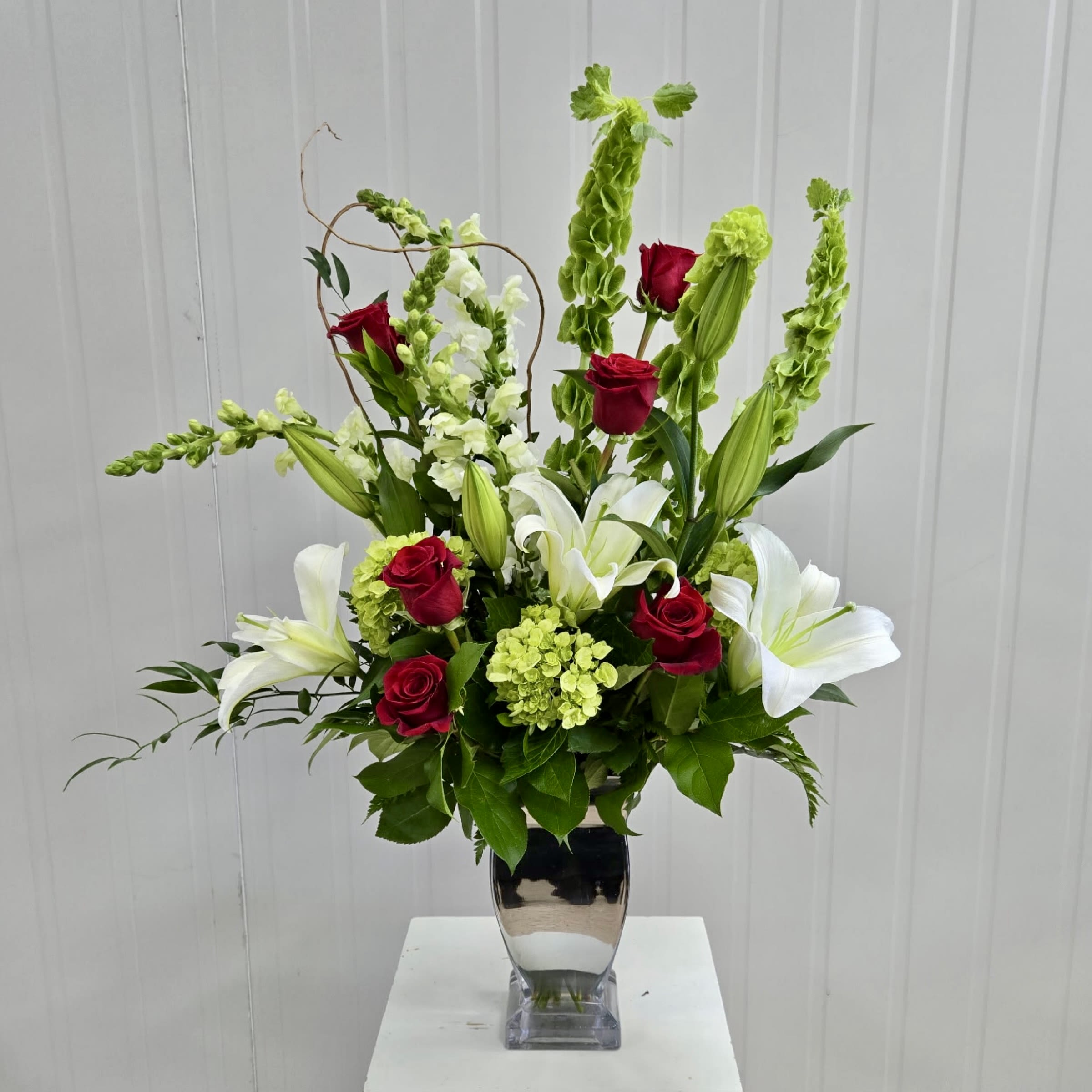 Passion And Peace Arrangement - This Silver Glass Vase Arrangement Includes Red Roses, Bells of Ireland, Green Mini Hydrangea, White Lilies, White Snapdragon and Curly Willow. Or as Similar as Possible. 