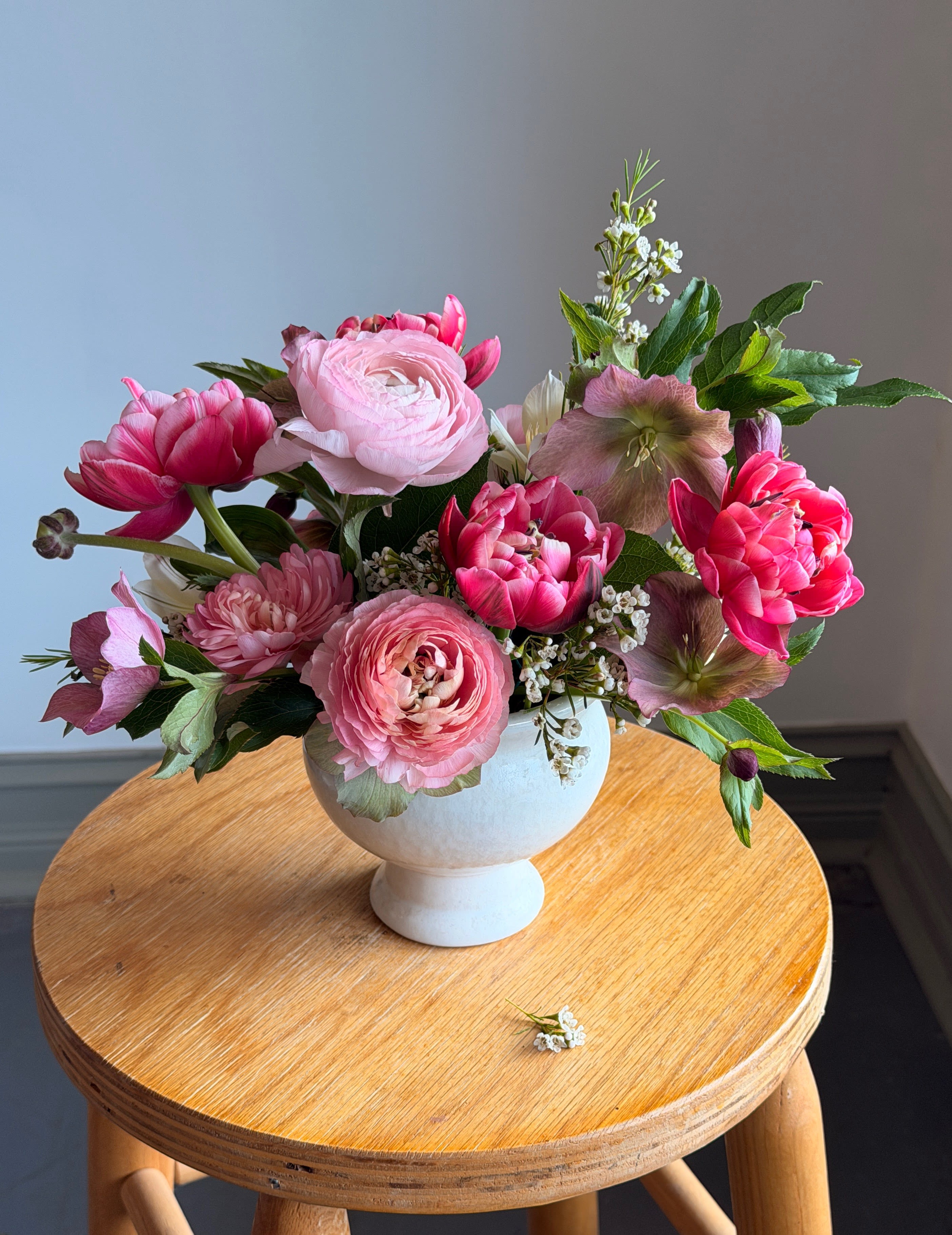 Pink floral arrangement in a white pedestal vase