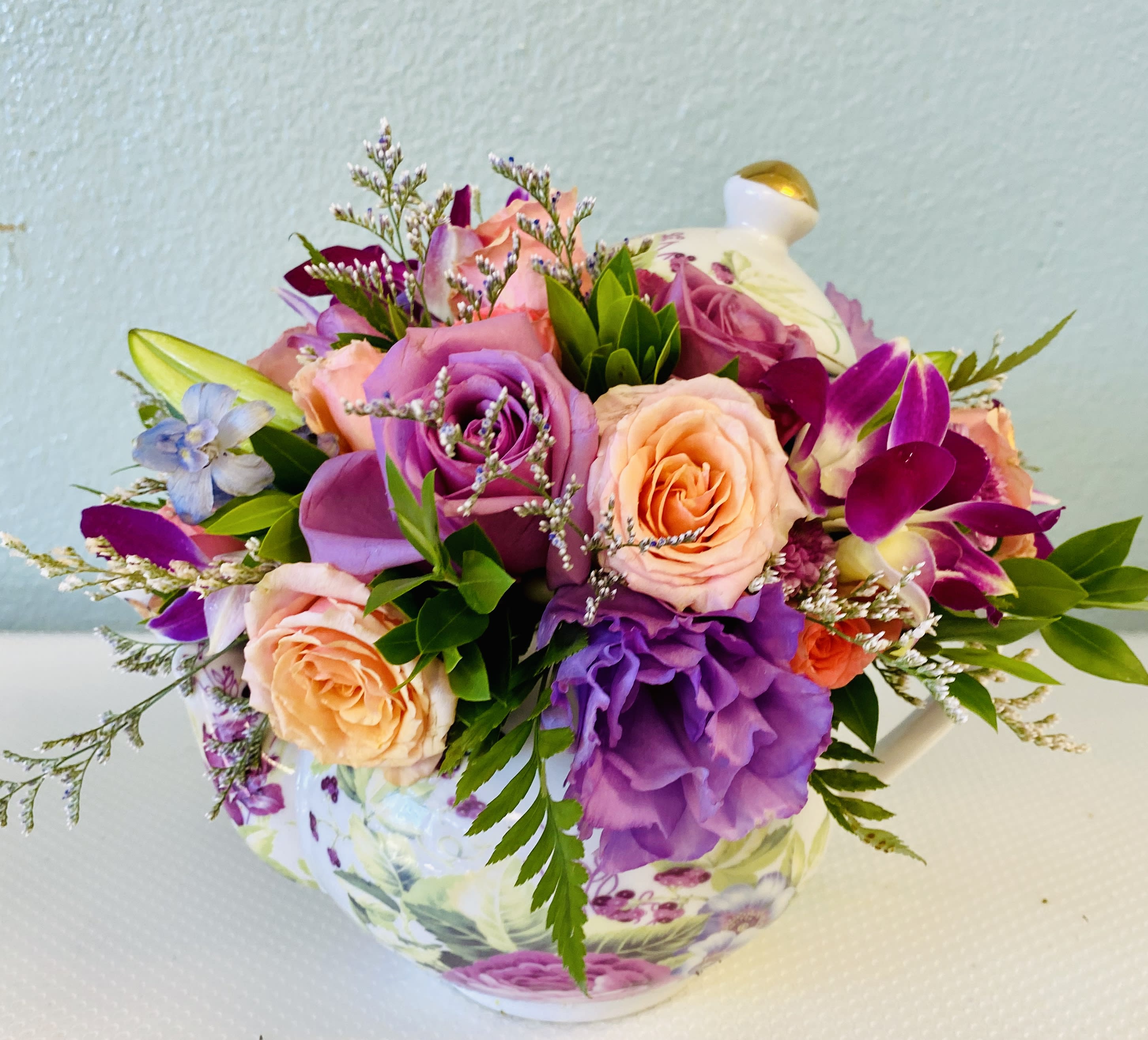 Teana's Treasure! - A lovely keepsake flower pot will be filled with seasonal purple and peach blossoms!  Here we used full size and mini garden roses, limonium and purple lisianthus.  *Orchids only available with the Premium version.