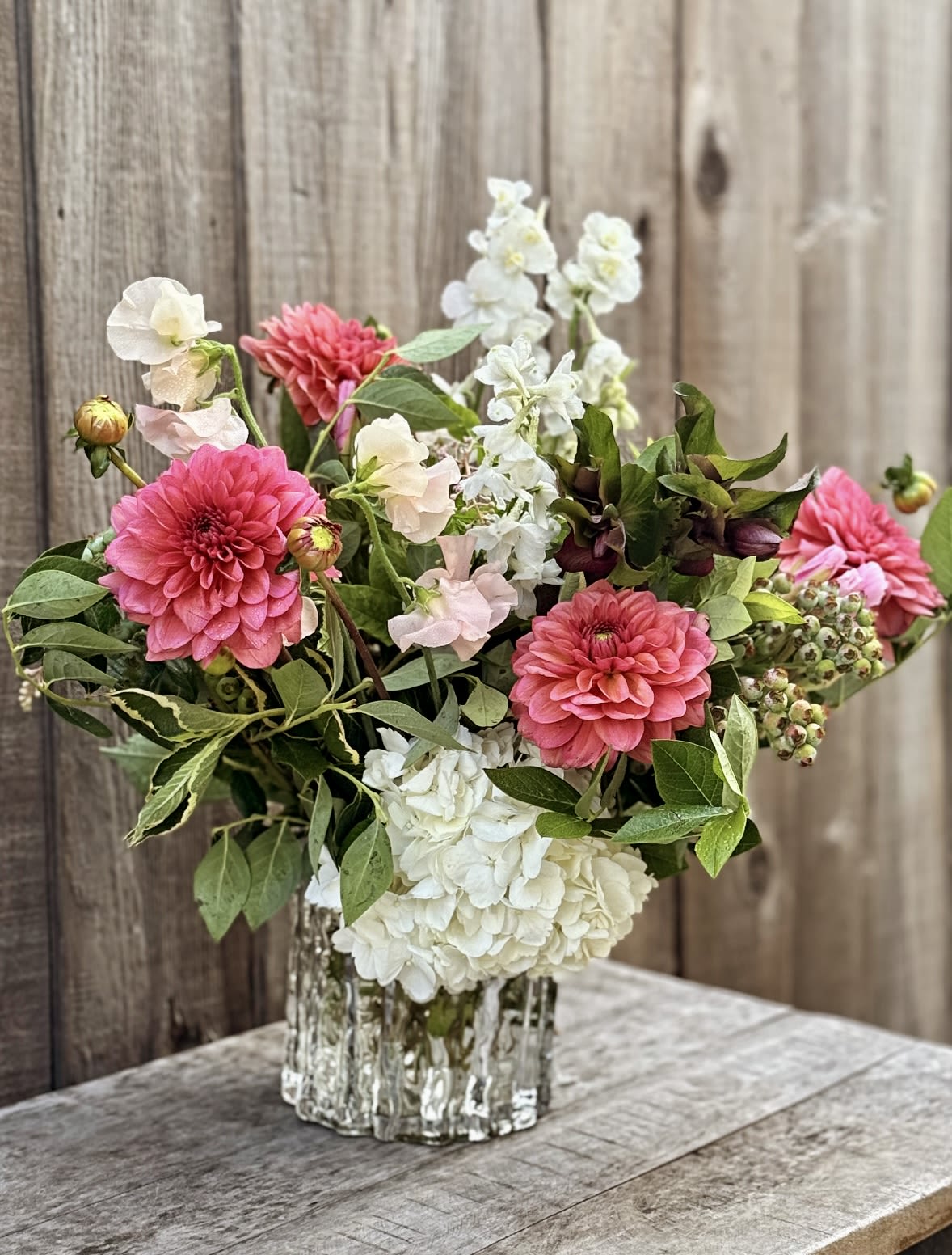 Pink and white flowers arranged in a clear glass vase